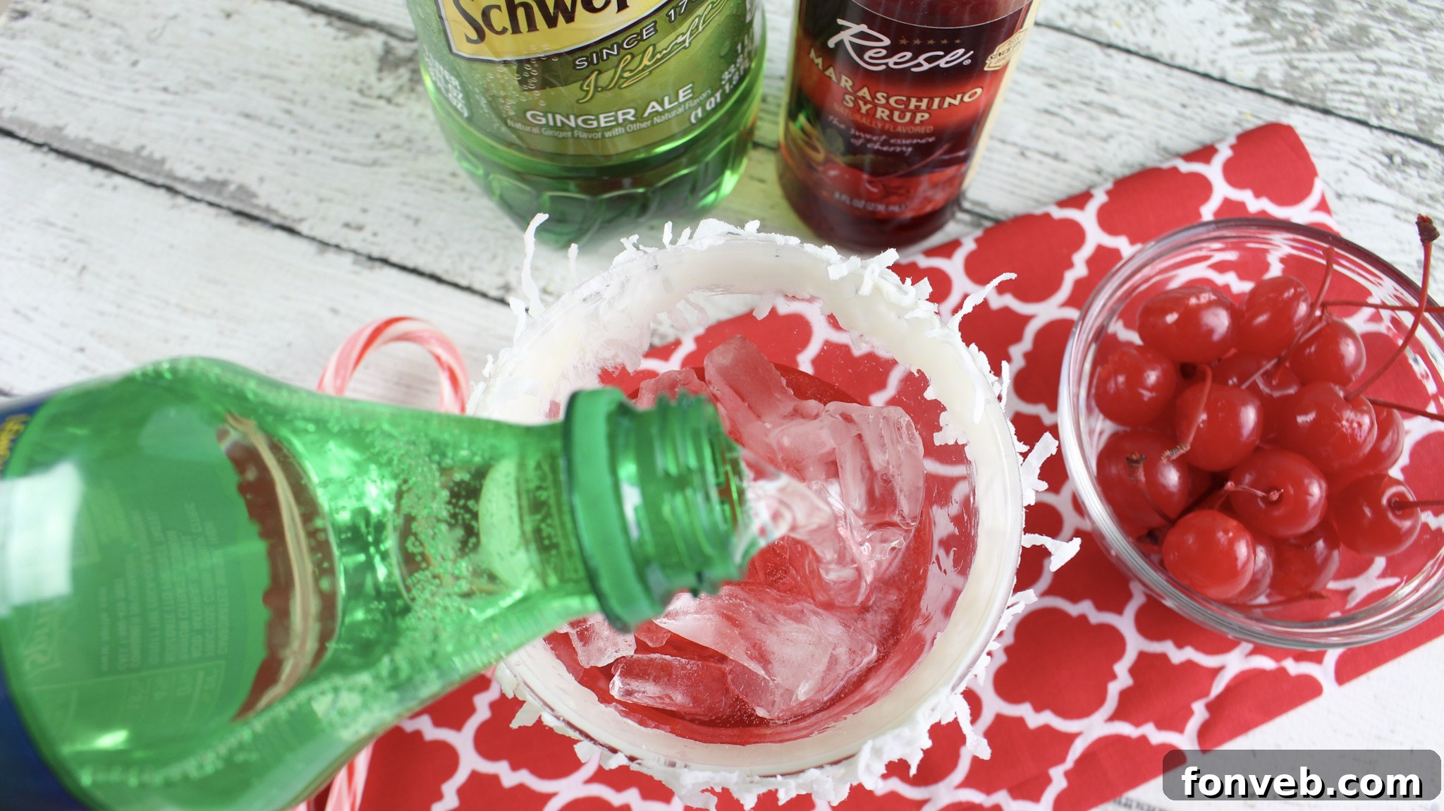 Ingredients for Santa Hat Cocktails laid out on a table, including coconut rum, grenadine, ginger ale, cherries, and candy canes.