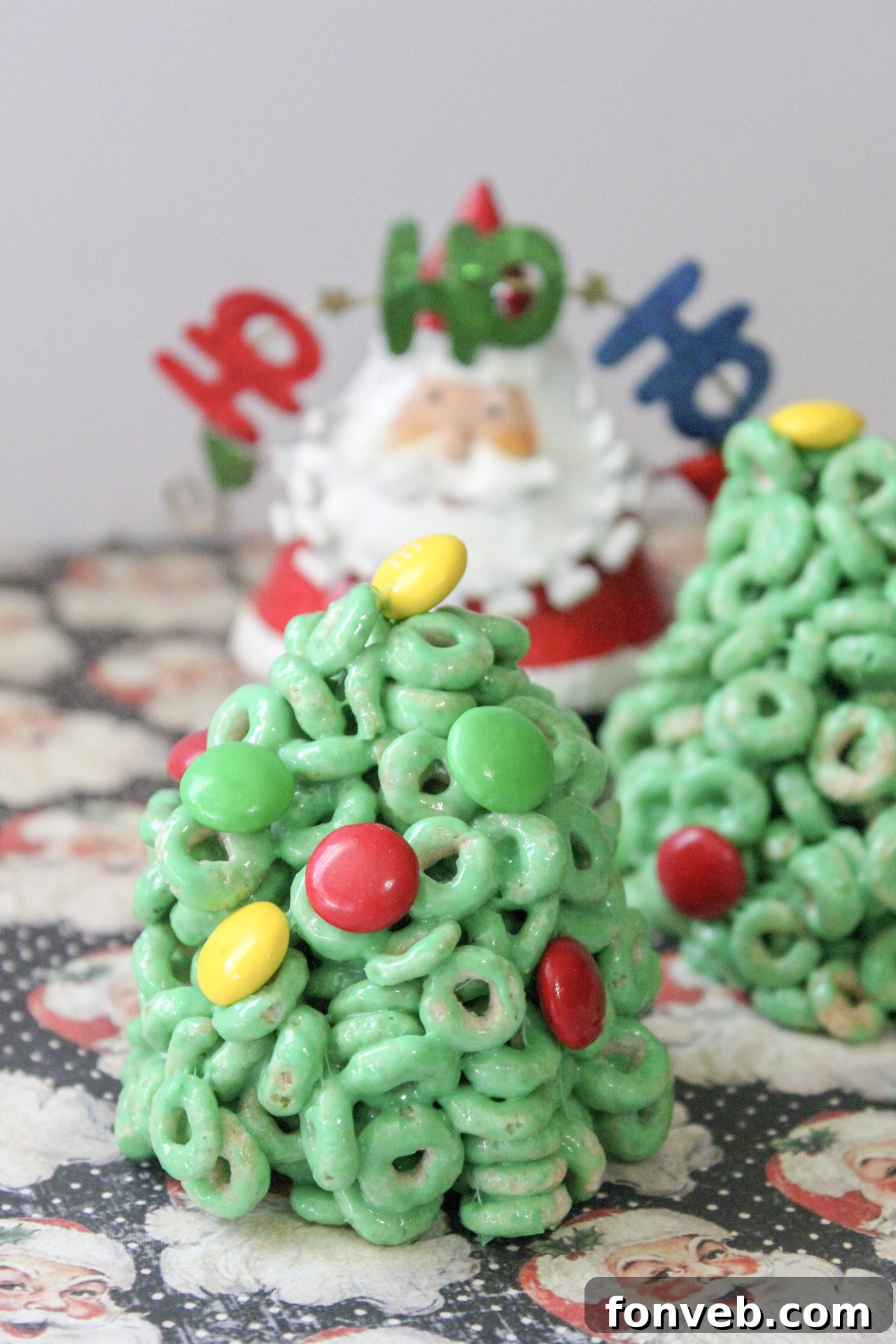 Close-up of a hand holding a Cheerio Christmas tree treat, showing its texture and decorations