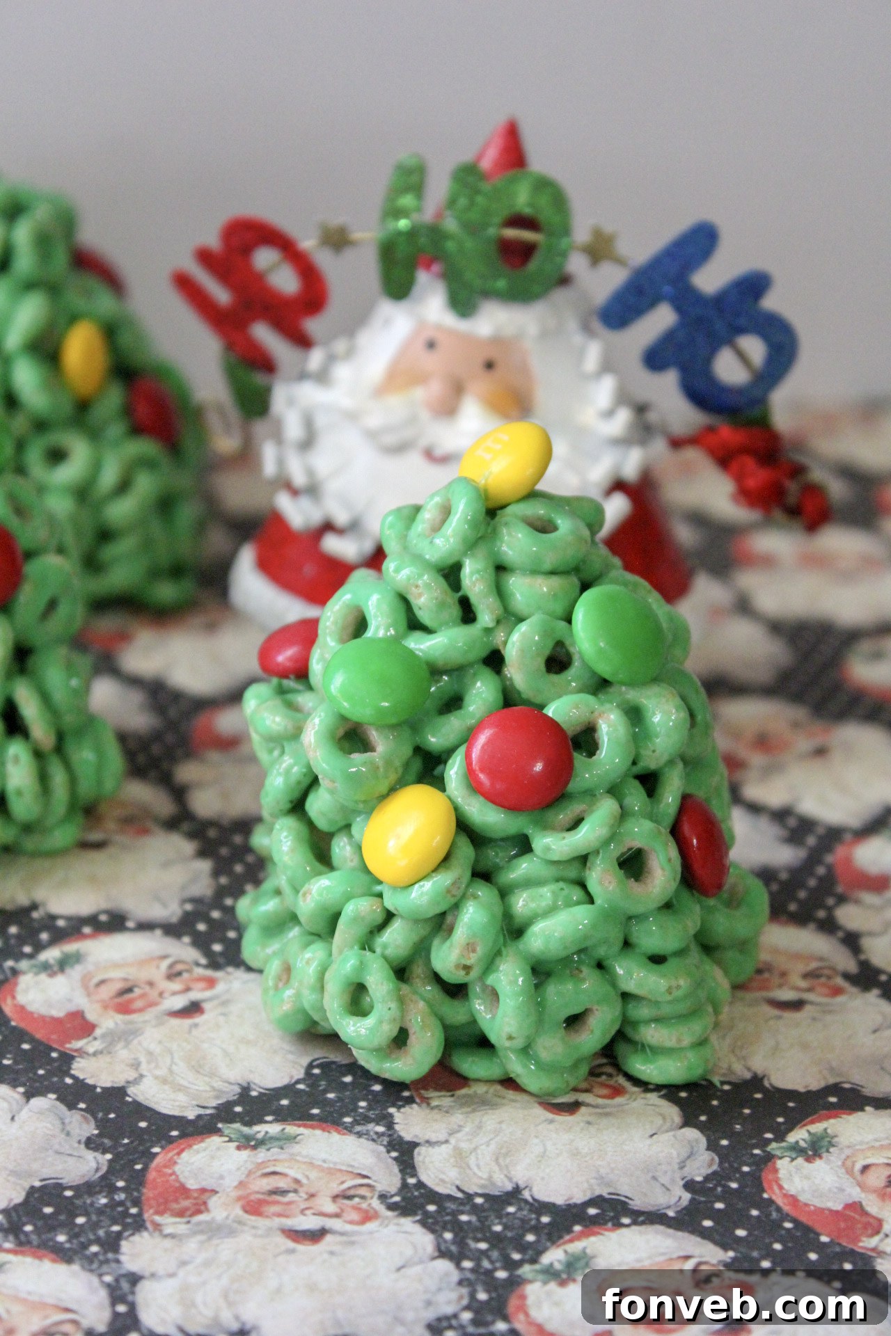 Several Cheerio Christmas tree treats arranged neatly, highlighting their vibrant green color and M&M ornaments
