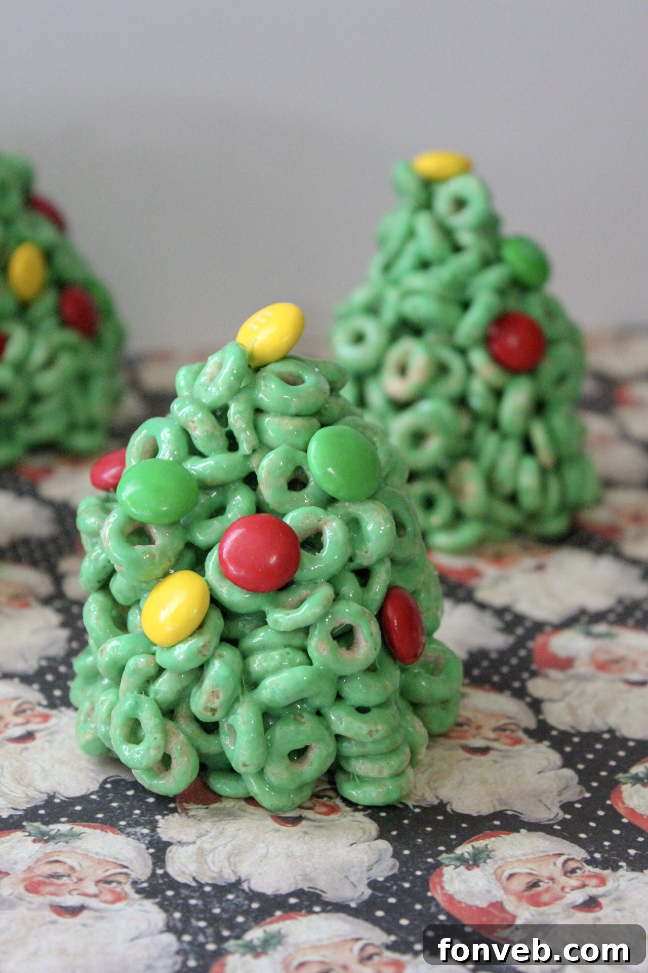 A close-up of a single Cheerio Christmas tree treat, showcasing its perfectly formed shape and colorful candy decorations