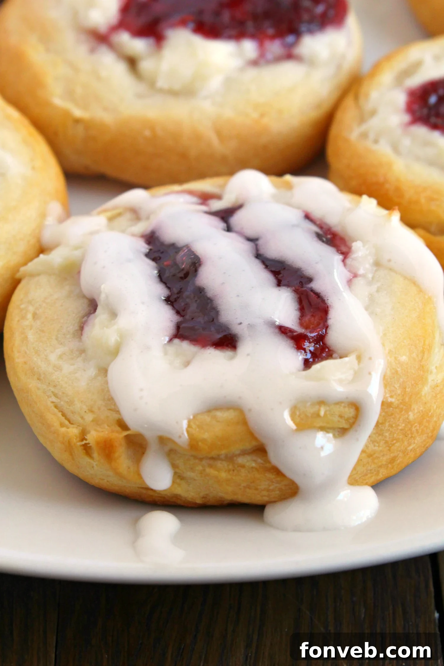Close-up of a baked raspberry cream cheese danish, showing the golden crust and vibrant filling.
