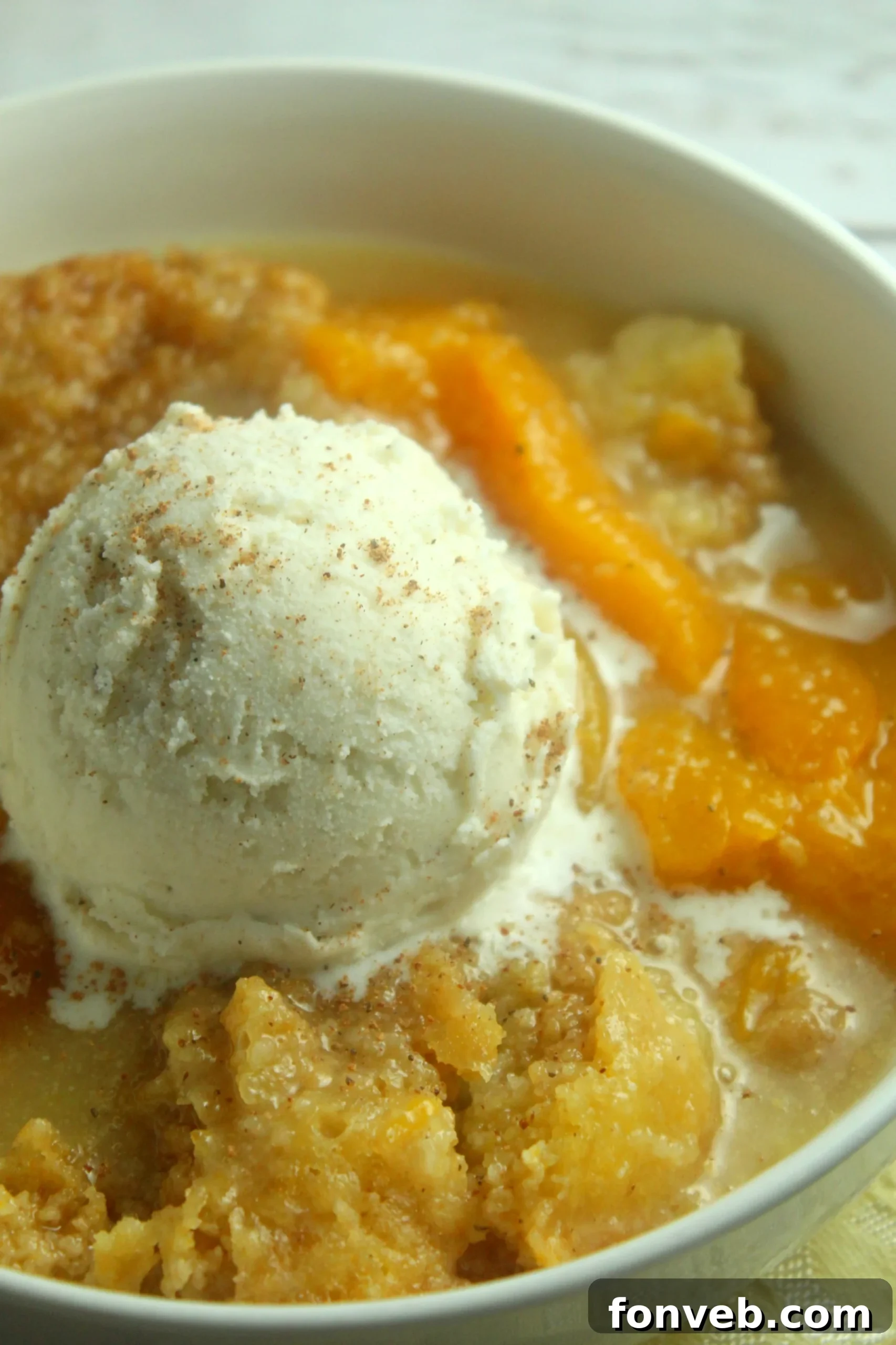 Crockpot Peach Perfection 2 Delicious slow cooker peach cobbler with a scoop of vanilla ice cream