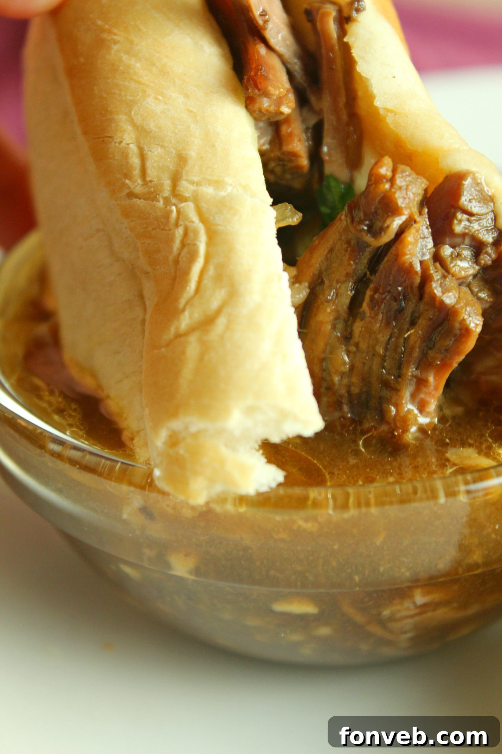 Delicious Slow Cooker French Dip Sandwiches piled high with tender beef and melted cheese, ready for dipping in au jus.