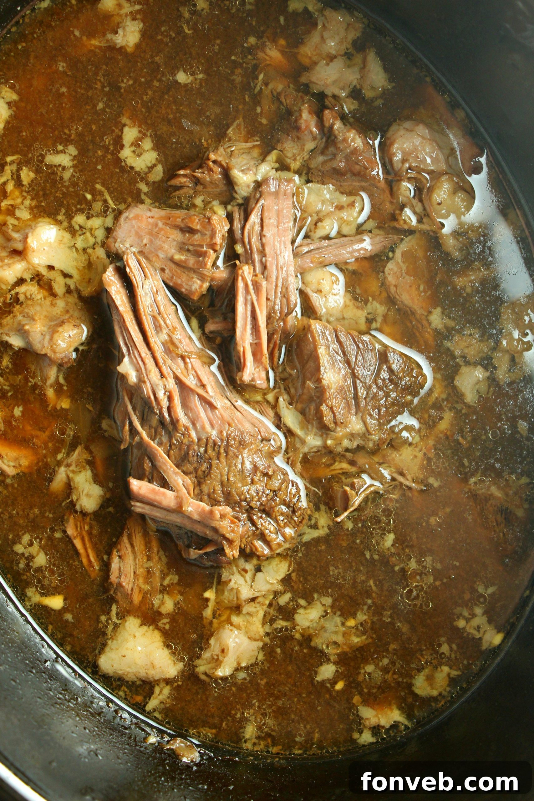 A French Dip sandwich being assembled on a toasted hoagie roll, highlighting the generous portion of beef.