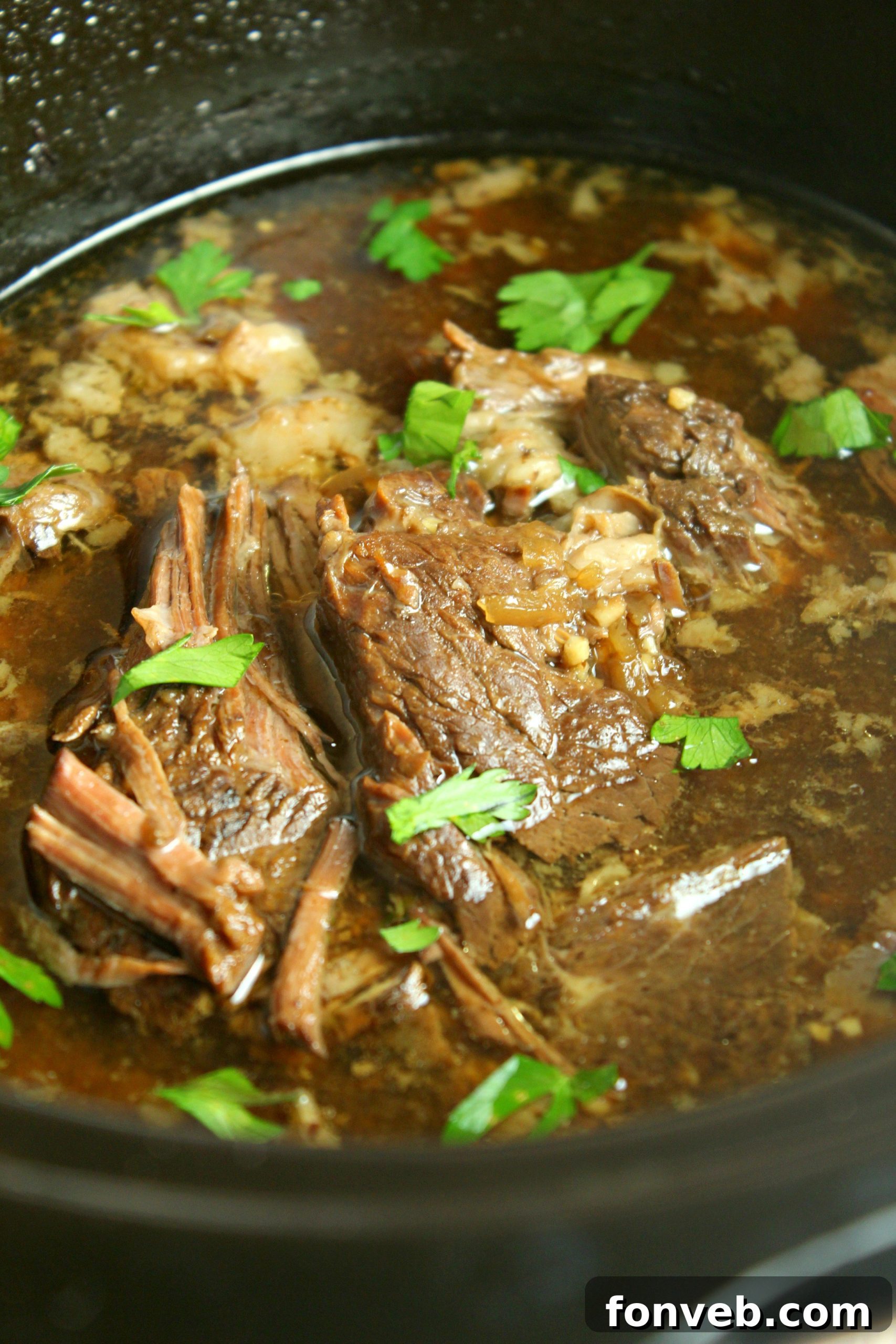A close-up of the shredded beef simmering in the slow cooker with the rich au jus.
