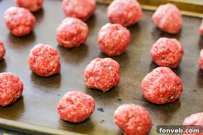 Rustic Tuscan Meatball Soup 4 A close-up shot of small, golden-brown baked meatballs arranged on a baking sheet, ready to be added to the soup.