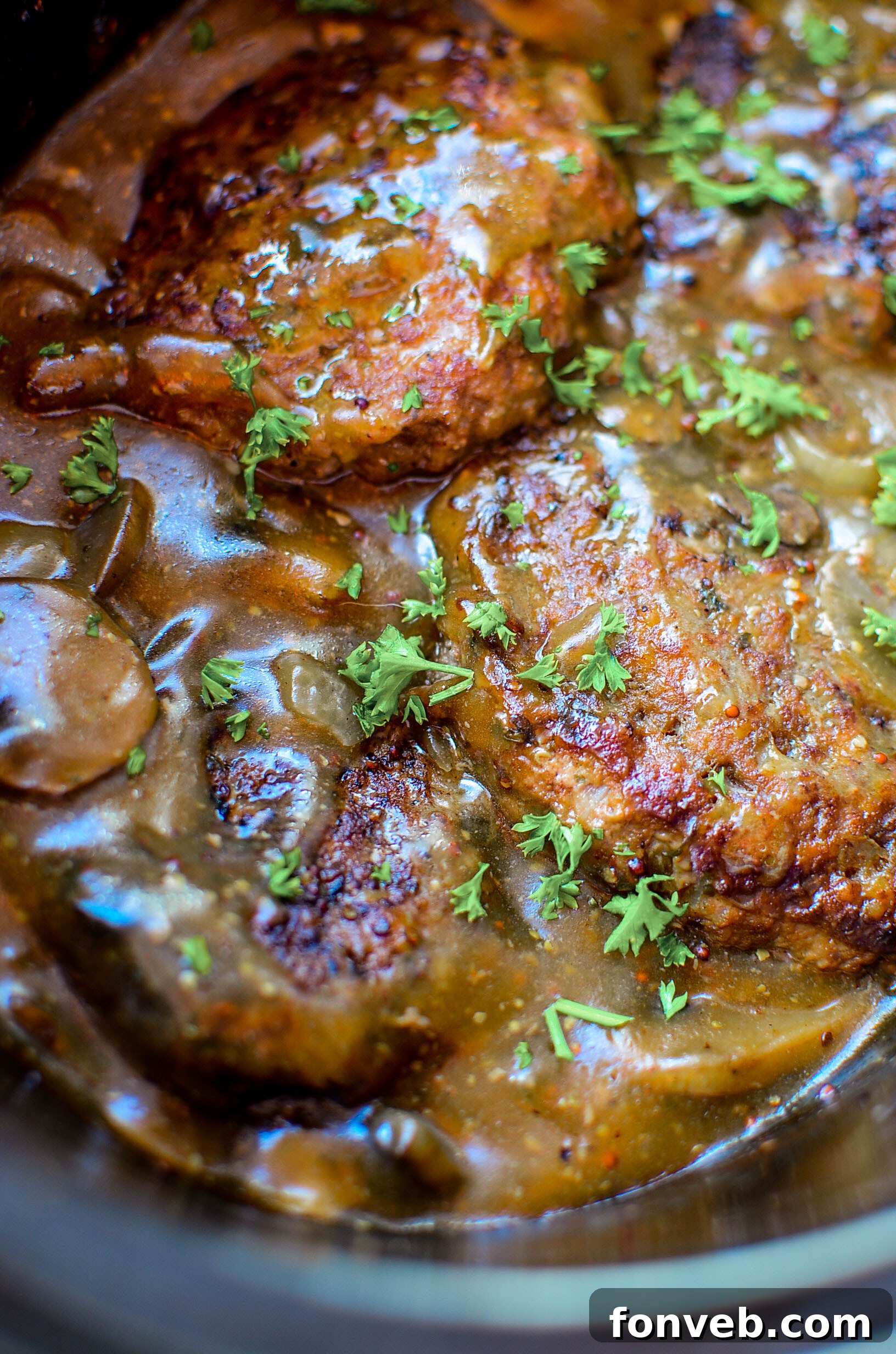 Close-up of a perfectly seared Salisbury steak patty in a skillet, showcasing the golden-brown crust before slow cooking.