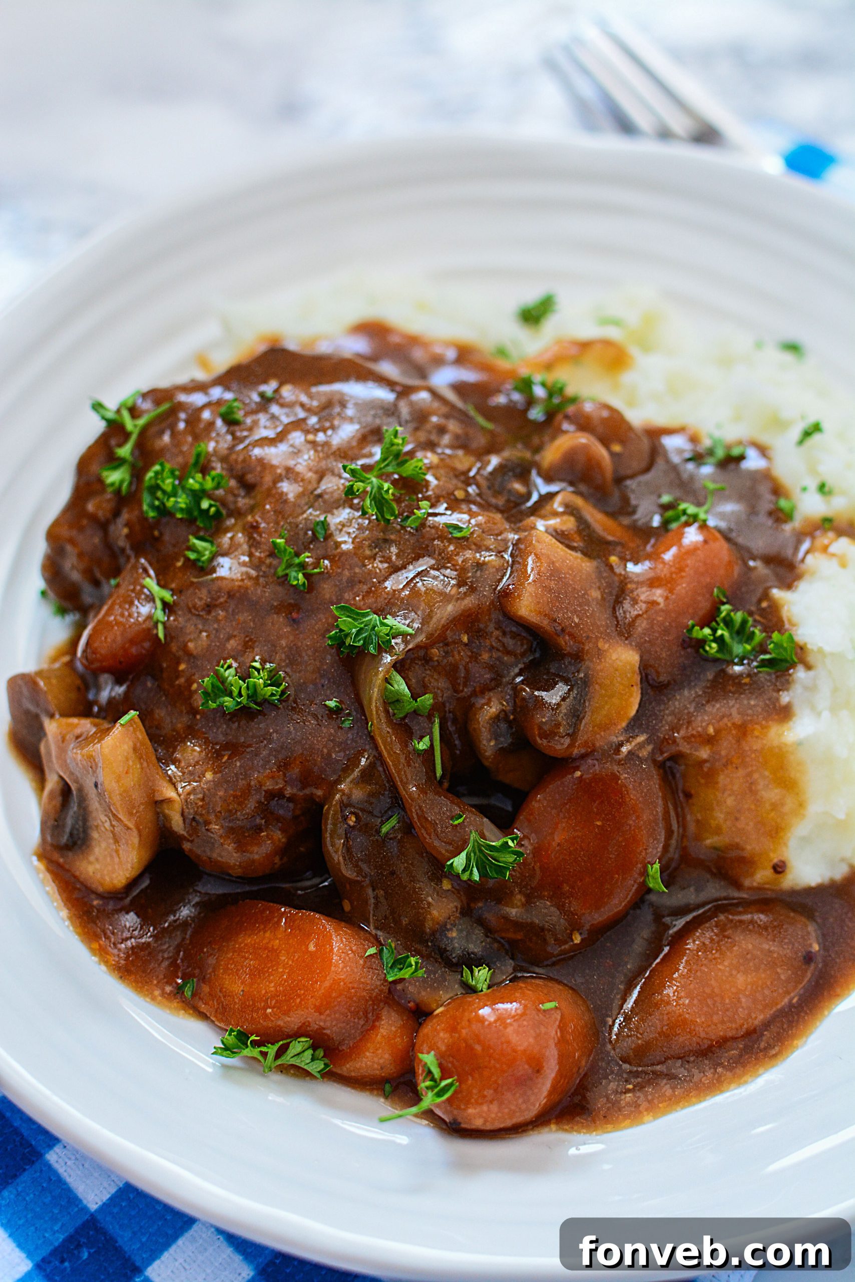 A close-up of a Salisbury steak patty in the slow cooker, perfectly cooked and surrounded by luscious gravy, ready for serving.