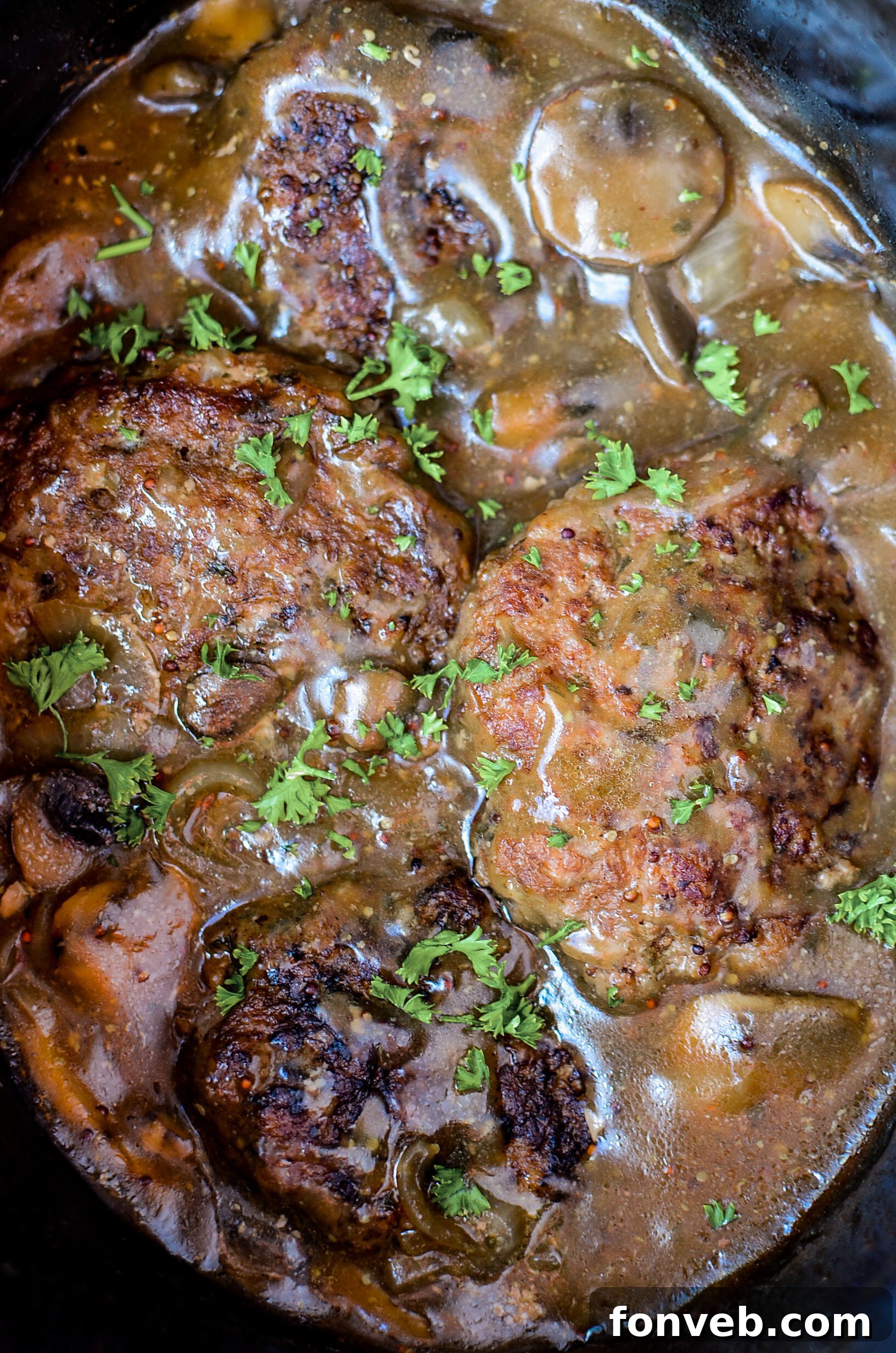 A close-up of the cooked Salisbury steak with thick gravy, garnished with fresh herbs, ready to be served as a comforting meal.