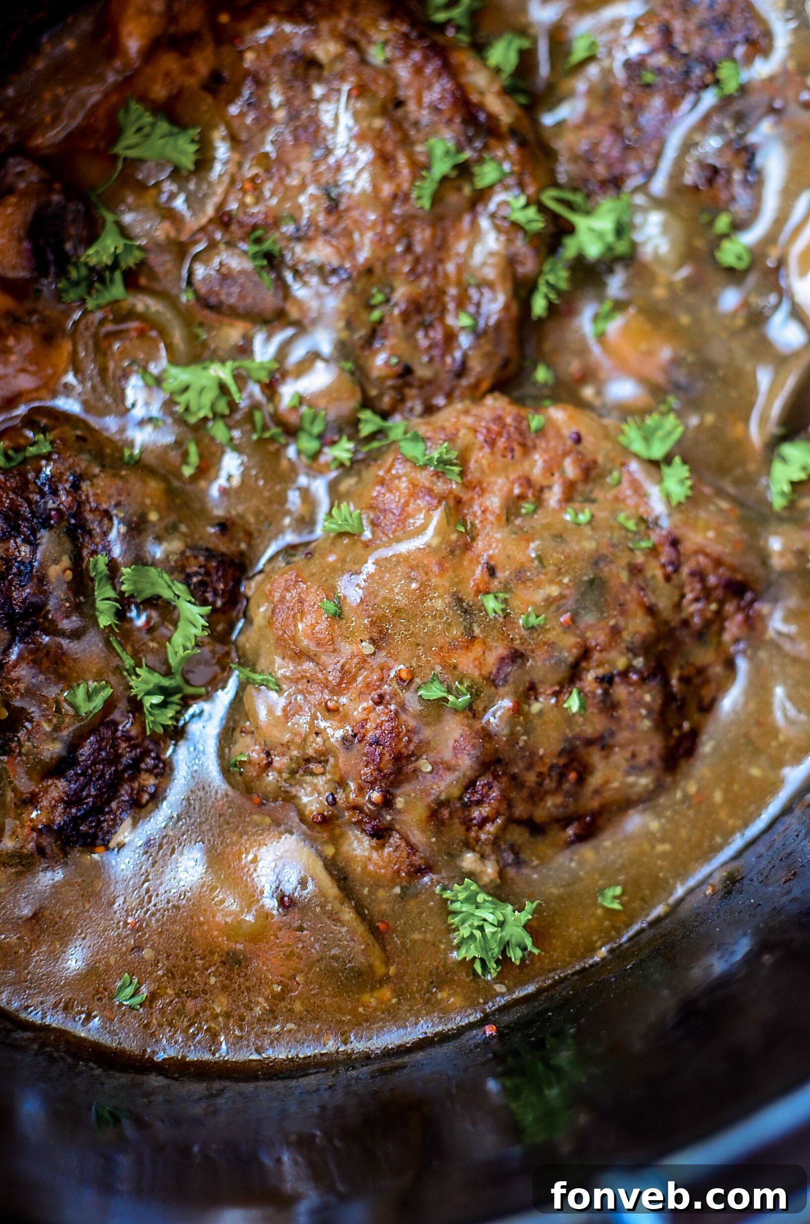 An overhead shot of a serving of Salisbury steak, with a focus on the rich gravy, mushrooms, and tender beef.