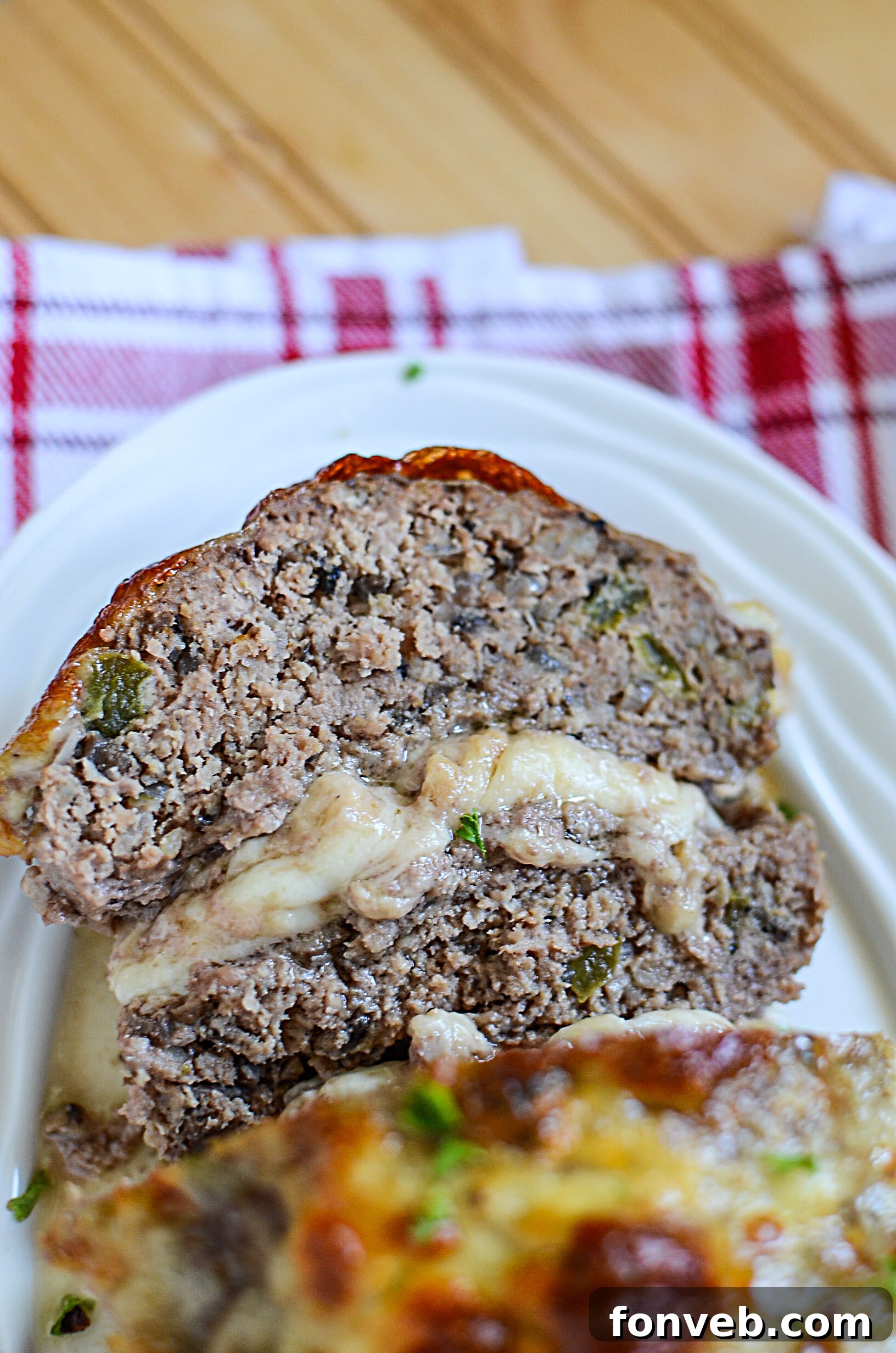 A close-up of a generous slice of Philly Cheesesteak Meatloaf, showing rich texture and cheese