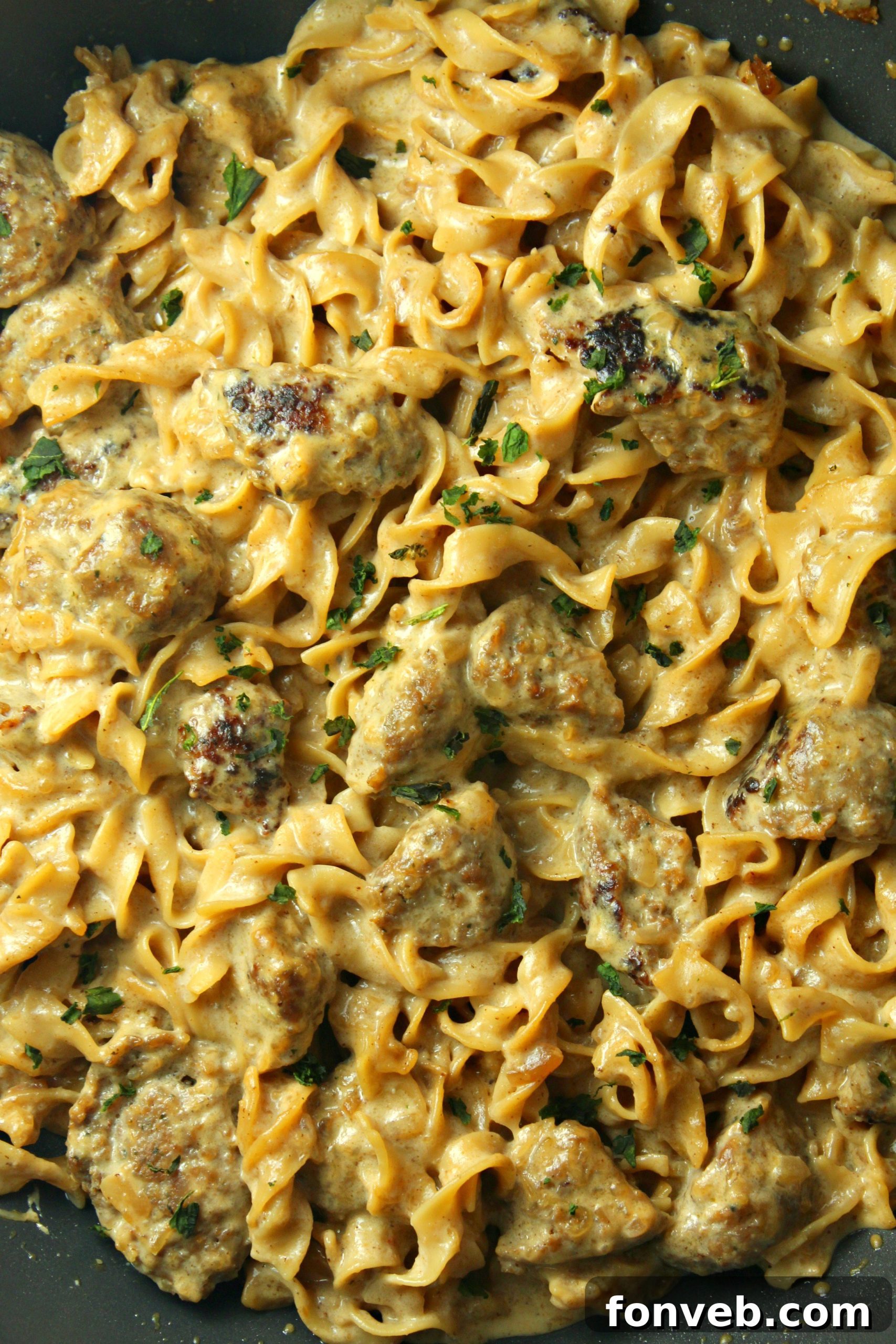 Velvety French Onion Sausage Pasta 4 A serving of Creamy French Onion Sausage Pasta with a fork, showing the rich texture and steam rising.