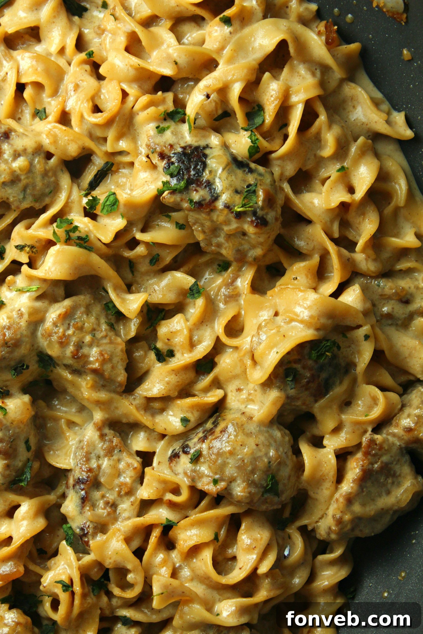 Velvety French Onion Sausage Pasta 9 A close-up of a serving spoon scooping Creamy French Onion Sausage Pasta, highlighting the creamy sauce and texture.