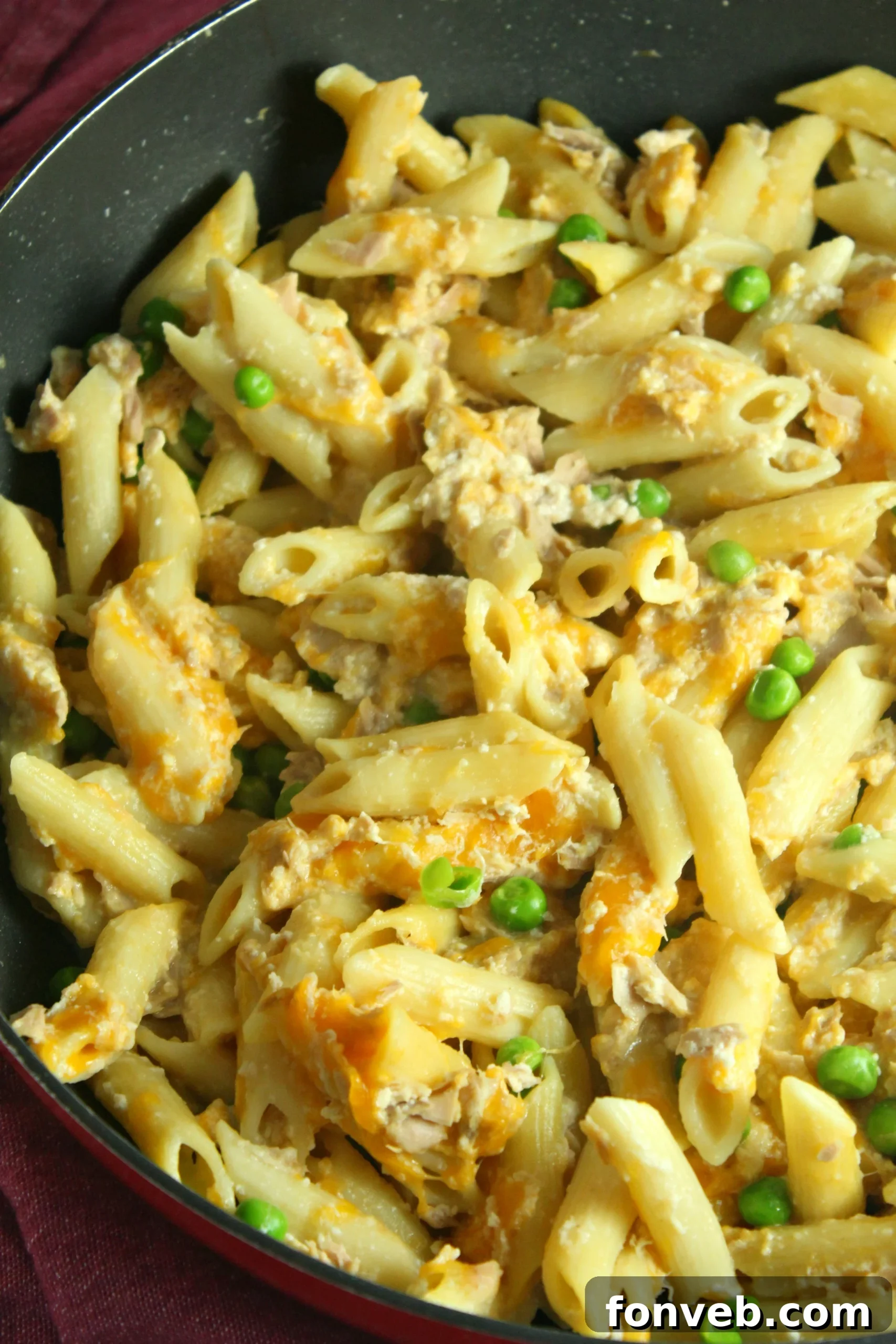 Golden Tuna Cheese Bake 2 Close-up of a bubbling, golden Cheesy Tuna Casserole, fresh from the oven, with a creamy sauce and penne pasta visible.