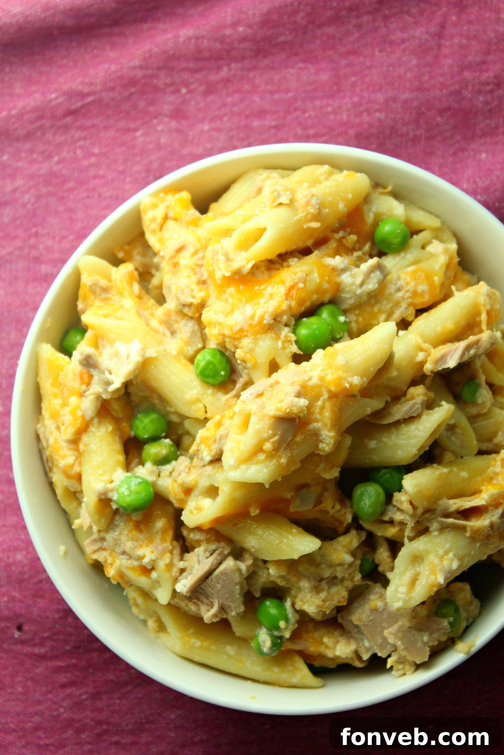 Golden Tuna Cheese Bake 3 Overhead shot of a large spoonful of Cheesy Tuna Casserole being served from a skillet, showcasing the rich texture and delicious ingredients.