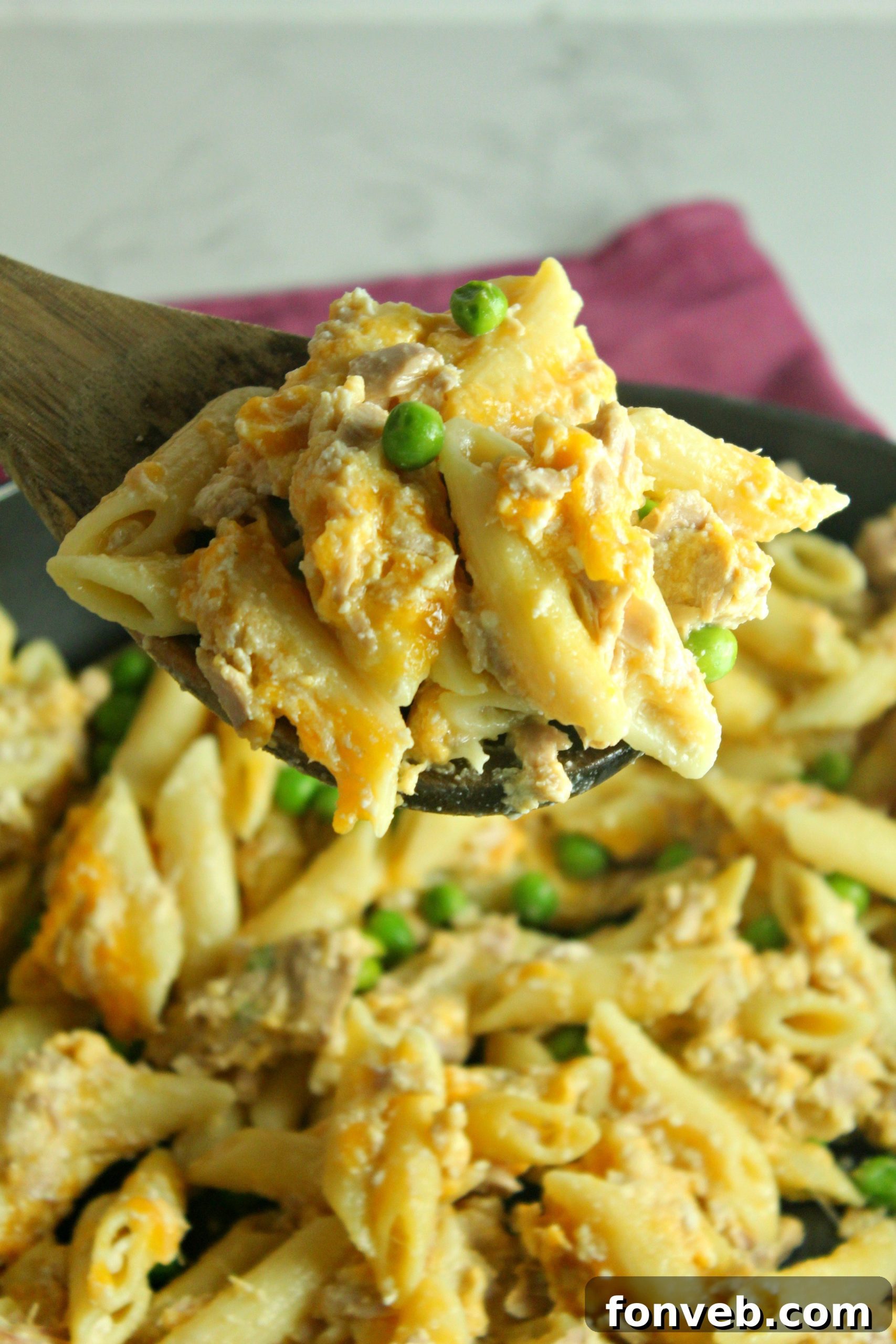 Golden Tuna Cheese Bake 4 A close-up view of a portion of Cheesy Tuna Casserole on a white plate, garnished with fresh parsley and ready to eat.