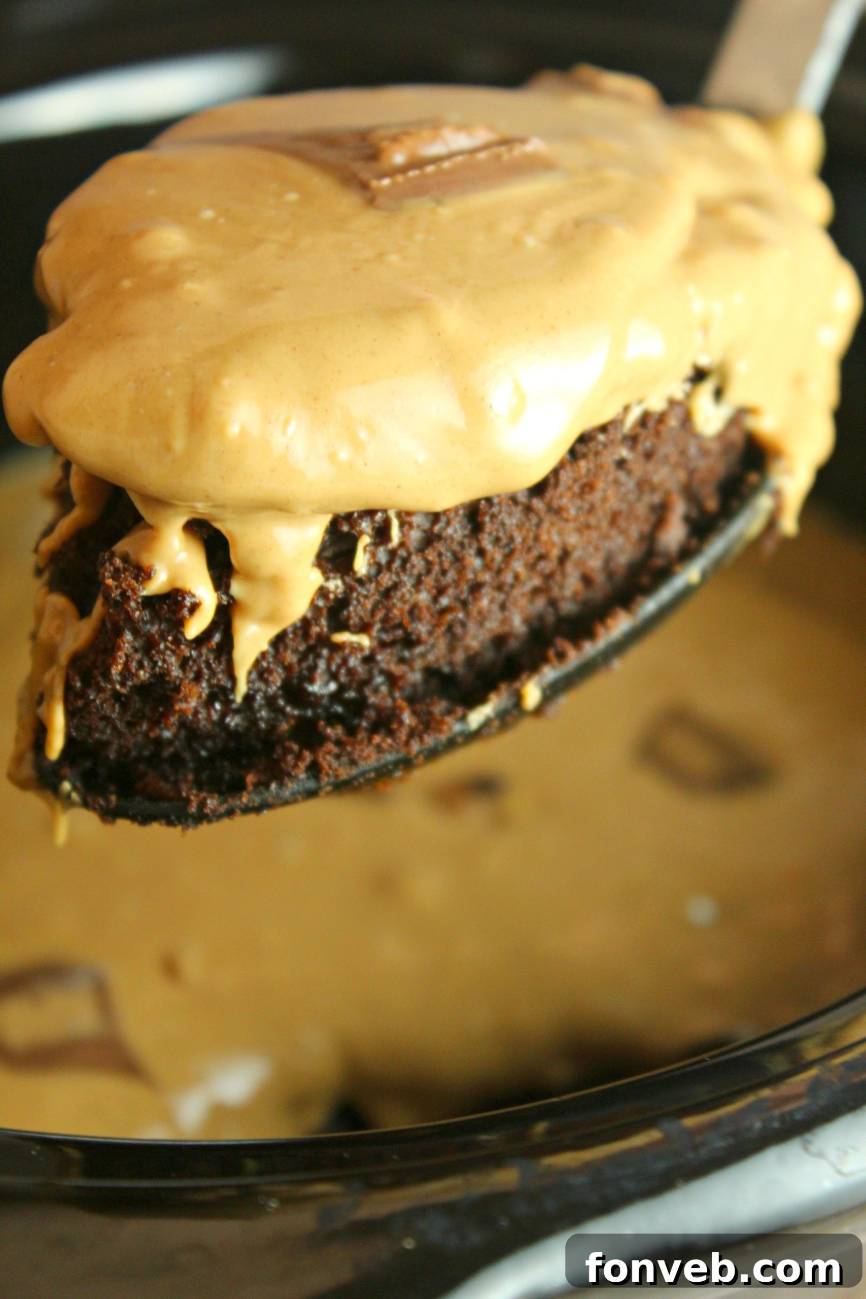 Slow Cooker Reeses Peanut Butter Chocolate Fudge Cake 2 A slice of slow cooker Reese's peanut butter chocolate cake topped with frosting and mini Reese's cups