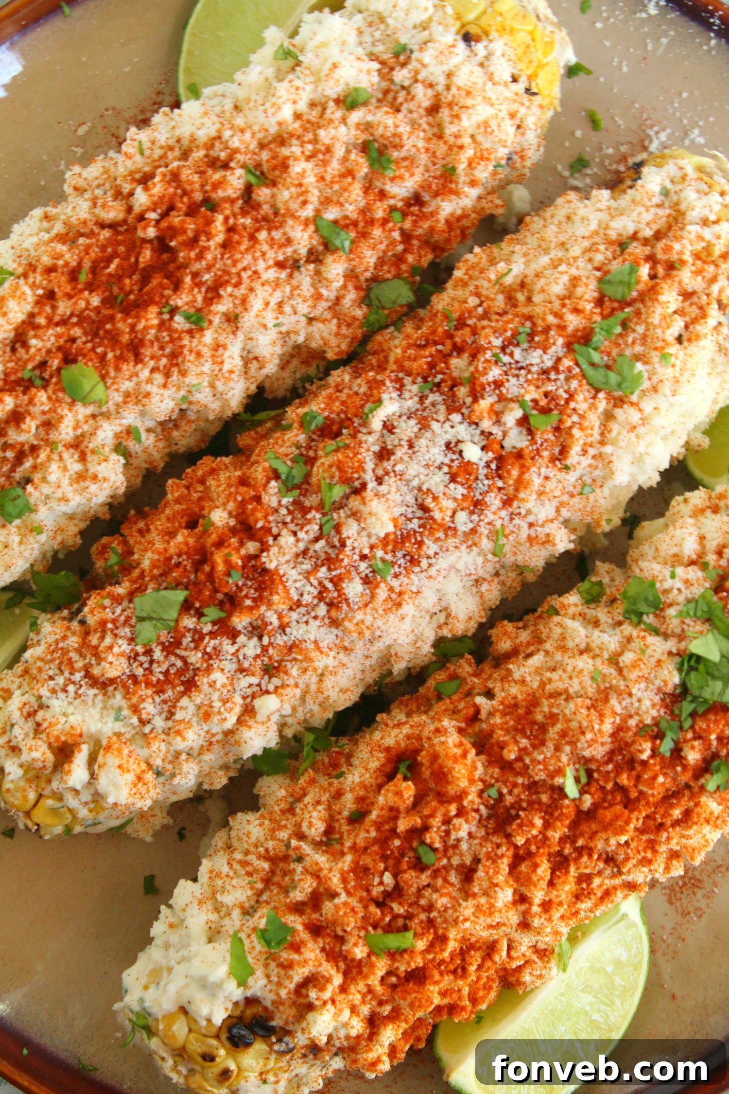 Mexican Street Corn on the cob, garnished with cilantro and chili powder.