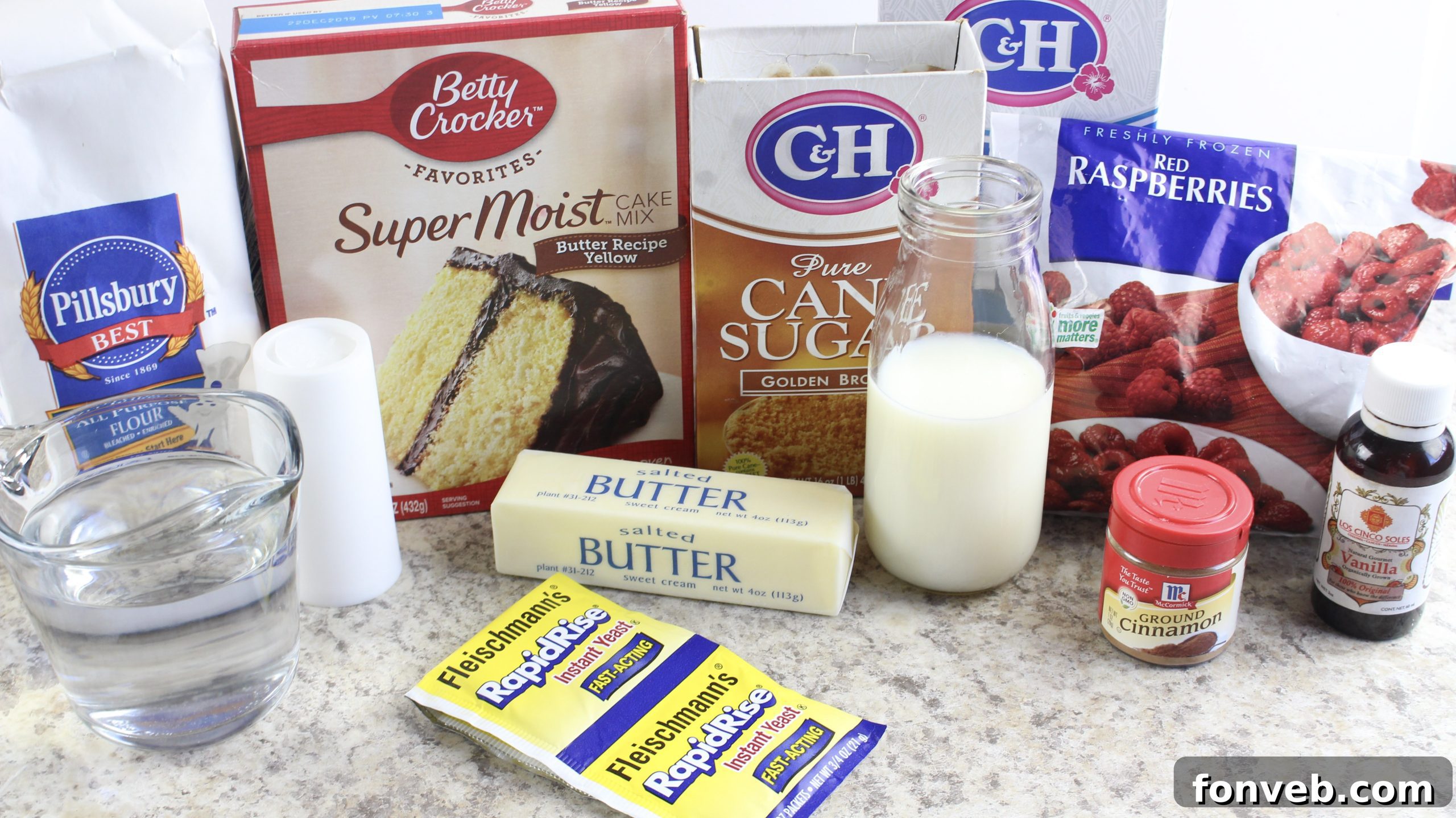 Velvet Raspberry Cinnamon Rolls 3 Two hands gently pulling apart a warm raspberry cinnamon roll, revealing the gooey raspberry and cinnamon swirl inside.