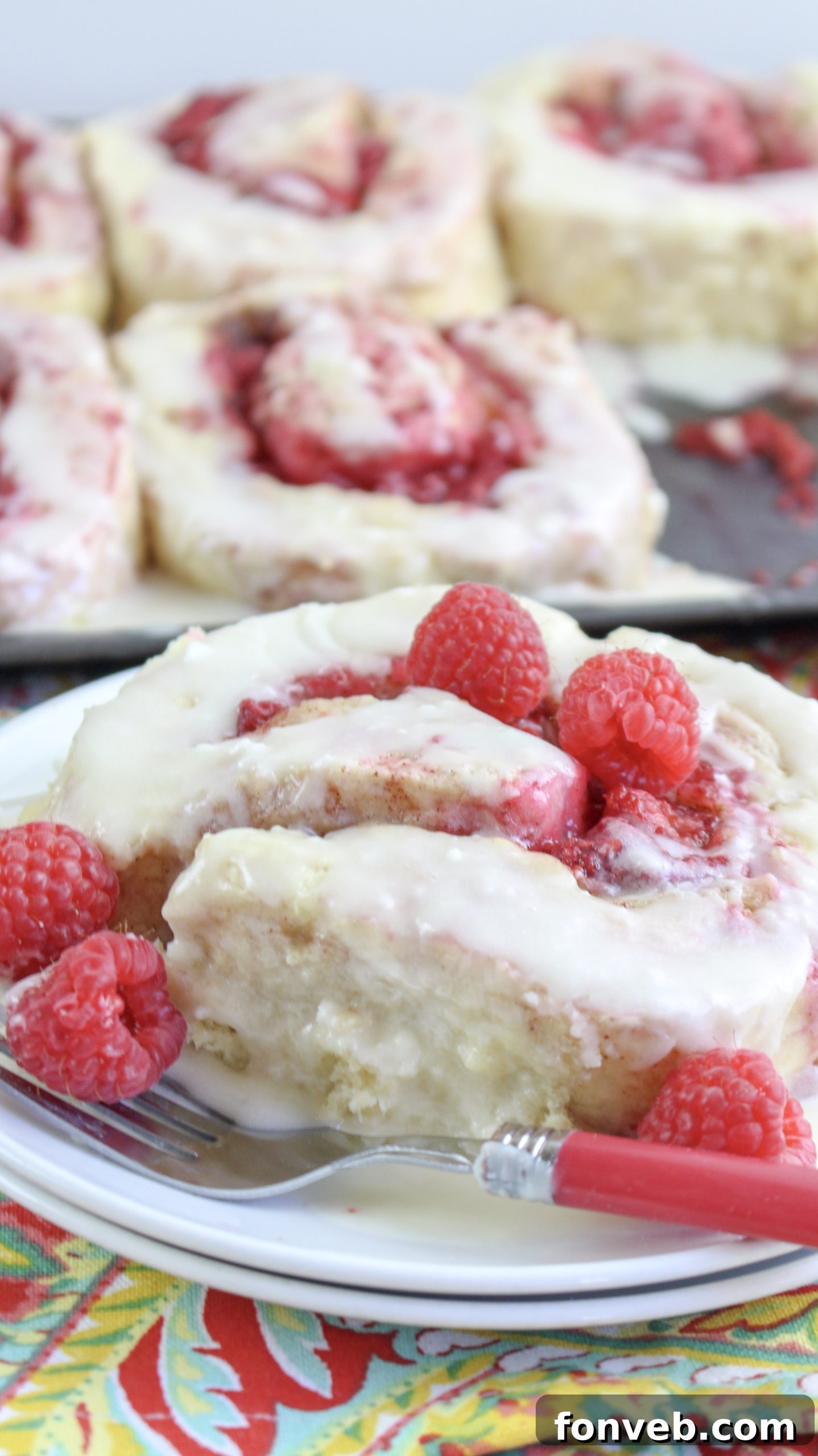 Velvet Raspberry Cinnamon Rolls 7 A panoramic view of an entire baking pan filled with golden-brown raspberry cinnamon rolls, generously covered in a thick layer of white icing.
