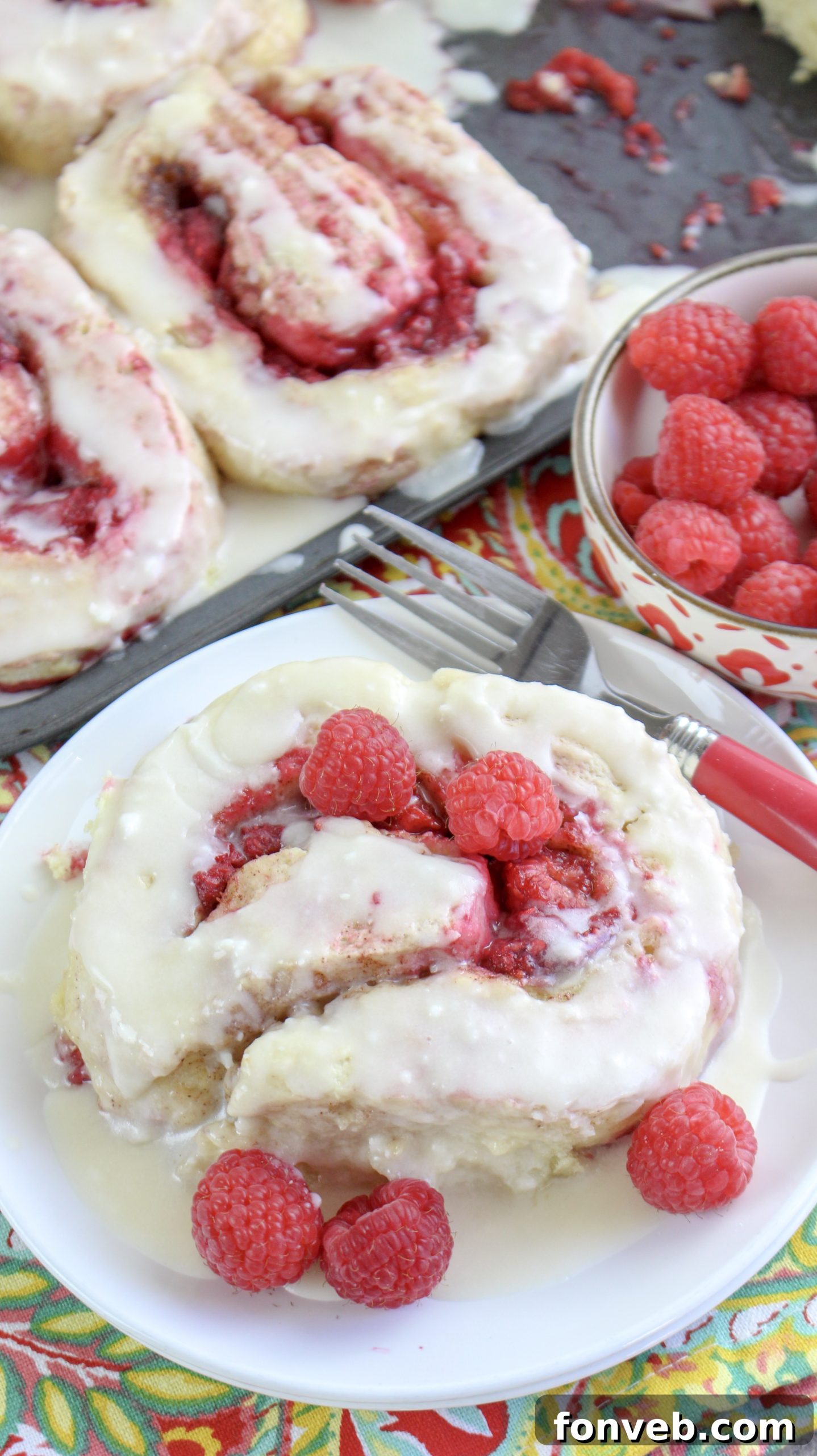 Velvet Raspberry Cinnamon Rolls 8 A single raspberry cinnamon roll on a plate, with a large glass of cold milk in the background, highlighting a classic pairing.