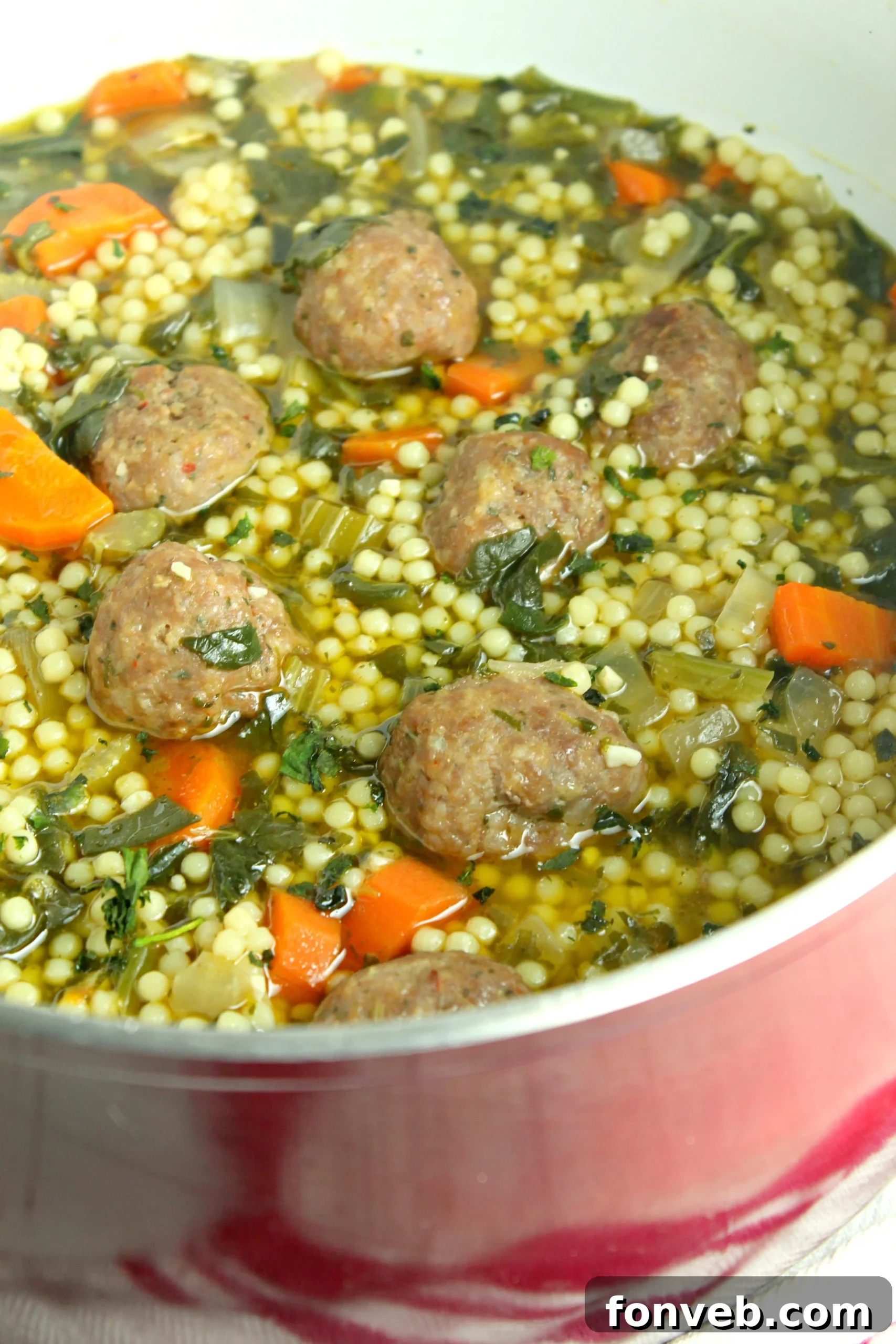A steaming bowl of authentic Italian Wedding Soup, showcasing tender meatballs, vibrant greens, and delicate pasta, garnished with fresh Parmesan cheese.