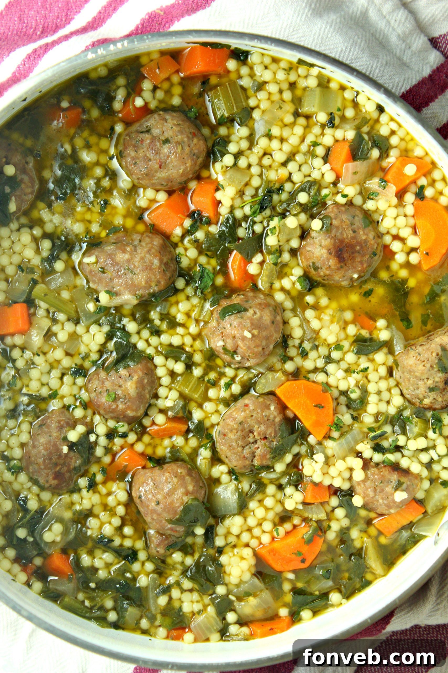 Close-up of a rustic bowl of Italian Wedding Soup, highlighting the savory broth, small pasta, and finely chopped vegetables.
