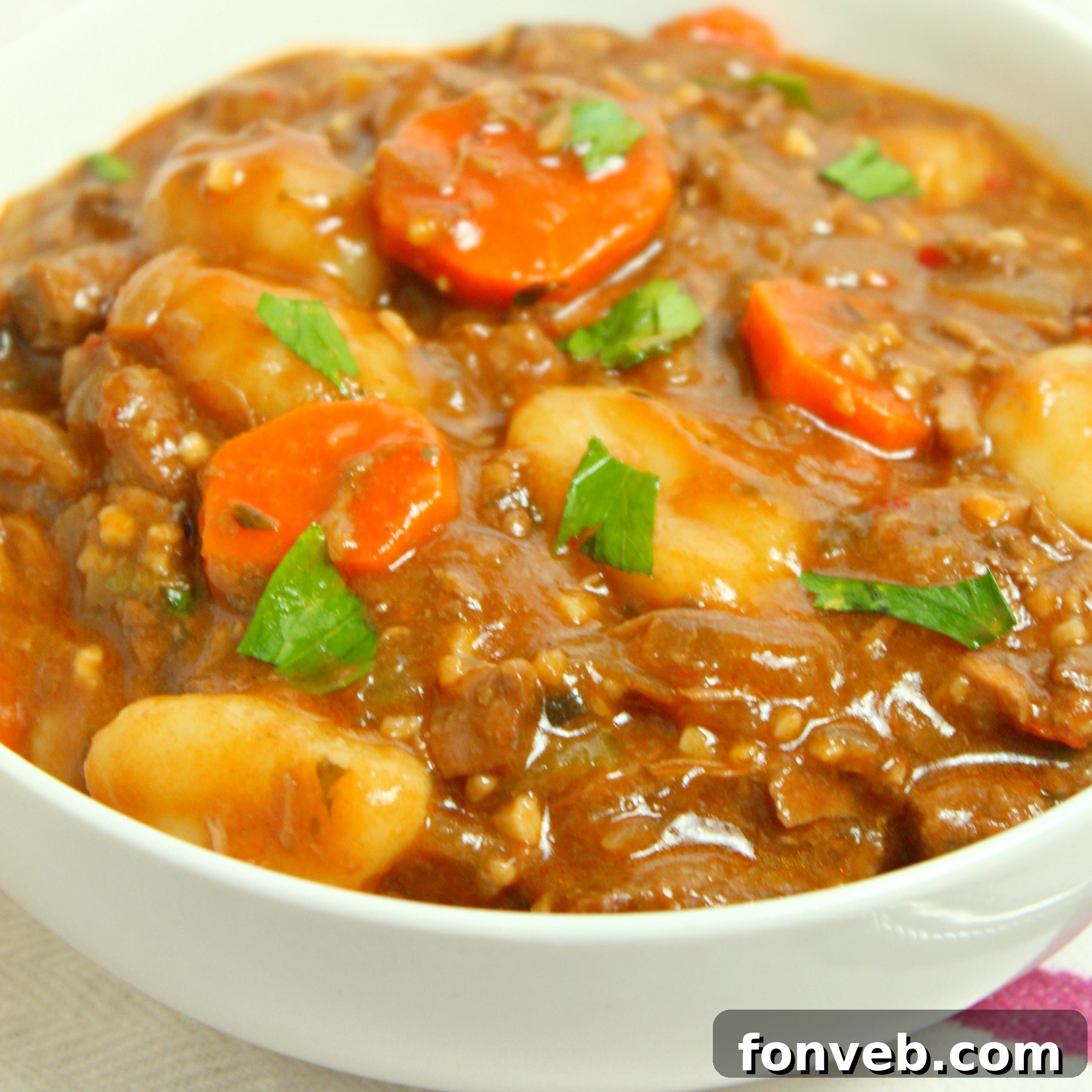 Several containers filled with chunky beef and gnocchi soup, ready for freezing or meal prepping.