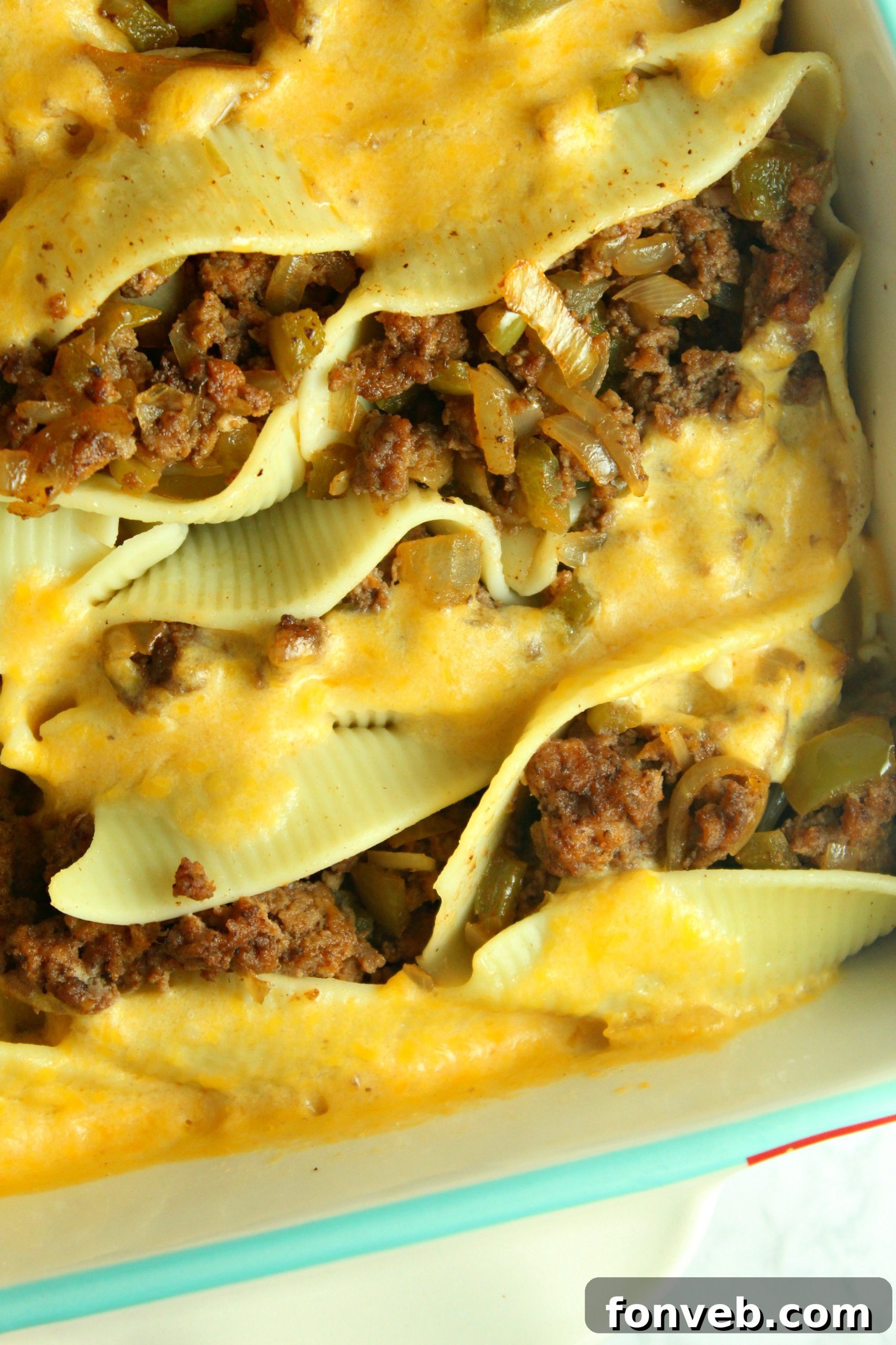 A close-up shot of rich and creamy Philly Cheese Steak Stuffed Shells in a baking dish, garnished with fresh parsley.