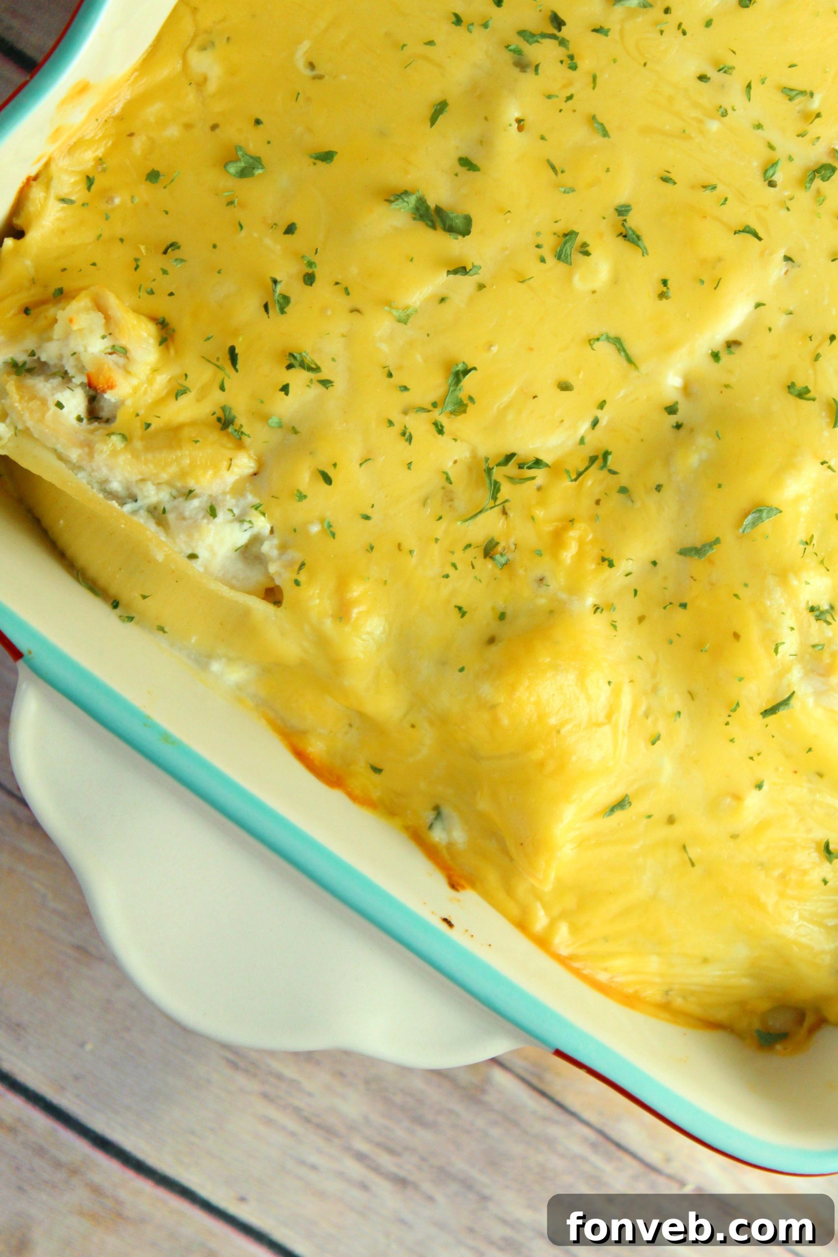 Creamy Garlic Chicken Stuffed Pasta Bake 6 Overhead shot of cheesy garlic chicken stuffed shells in a baking dish, with a spoon ready to serve.