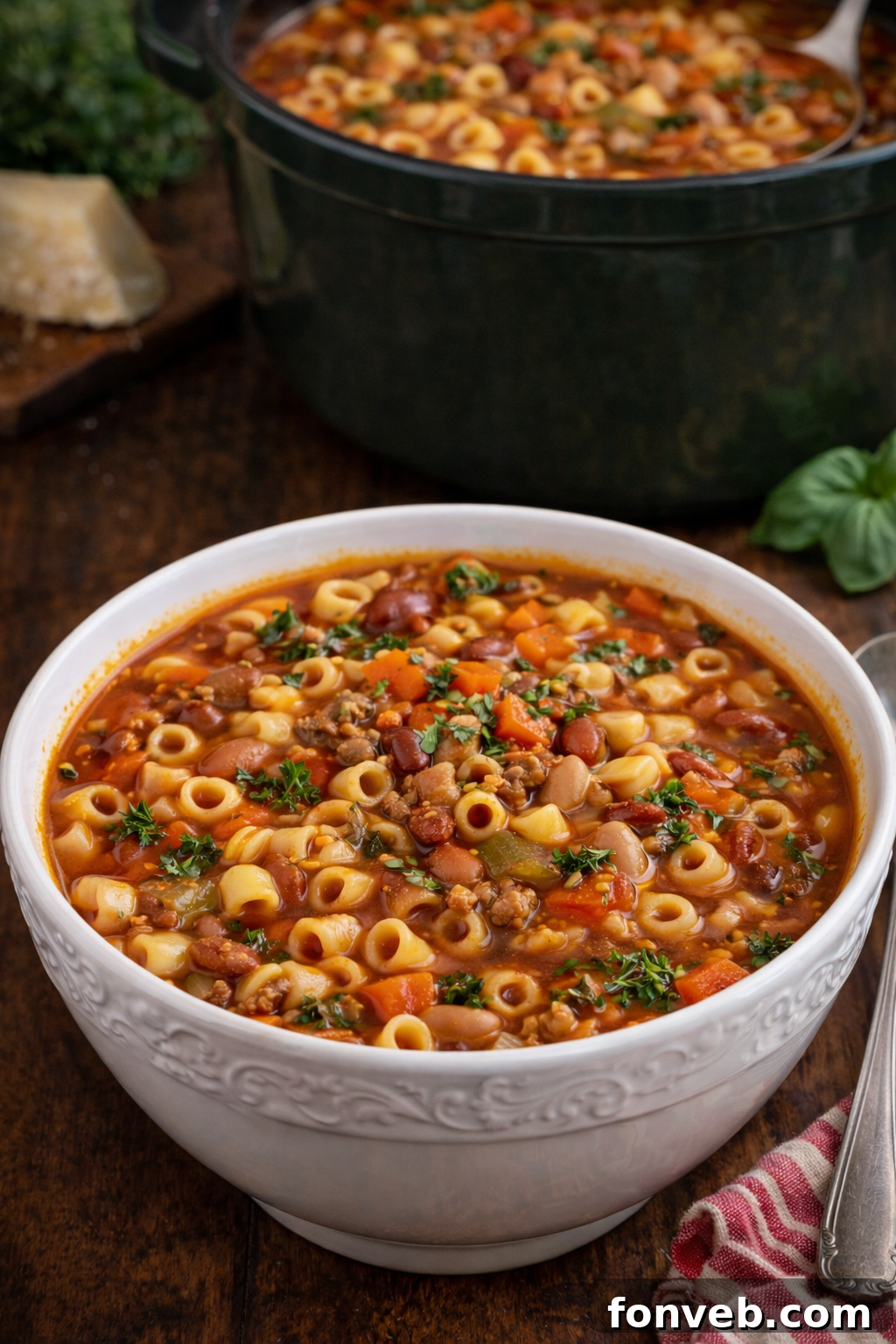 A white bowl of Ultimate Pasta e Fagioli Soup on a dark wooden table, ready to enjoy