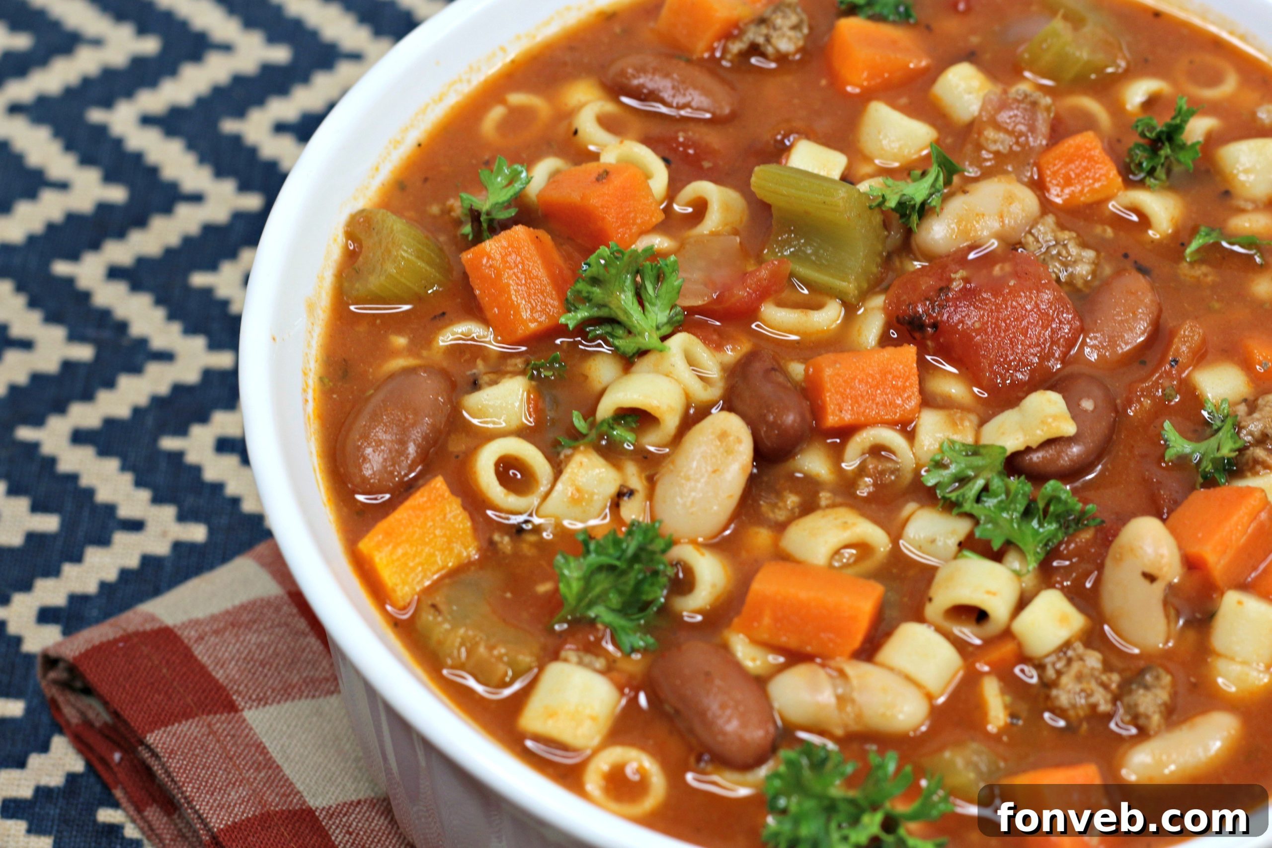 Ingredients for Pasta e Fagioli Soup laid out on a cutting board, including fresh herbs and diced vegetables