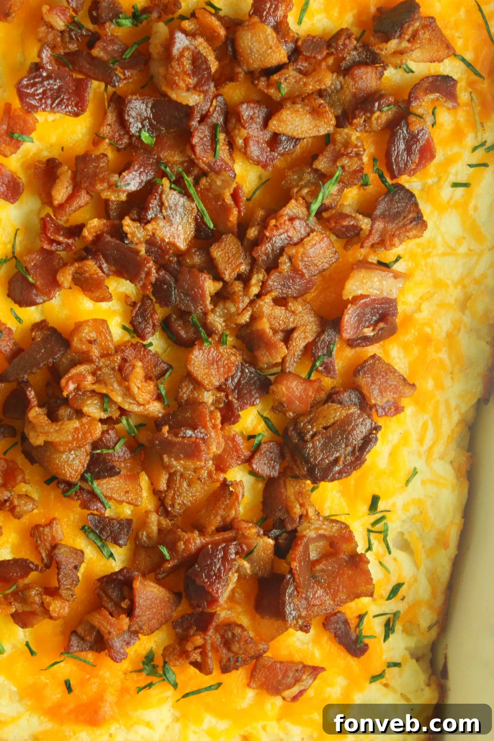 Ultimate Loaded Potato Bake 2 Close-up of a large loaded mashed potato casserole dish, golden brown with melted cheese and crispy bacon bits on top, ready to be served.