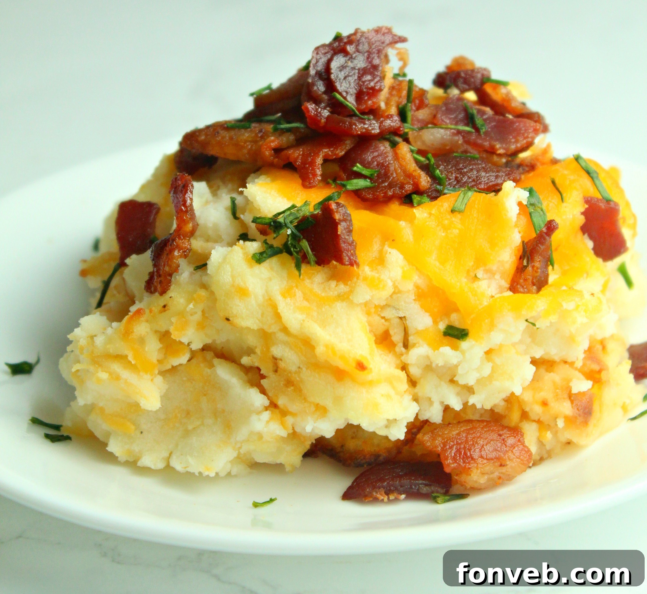 Ultimate Loaded Potato Bake 7 Loaded Mashed Potato Casserole, garnished with fresh herbs and more bacon, showcasing its rich texture.