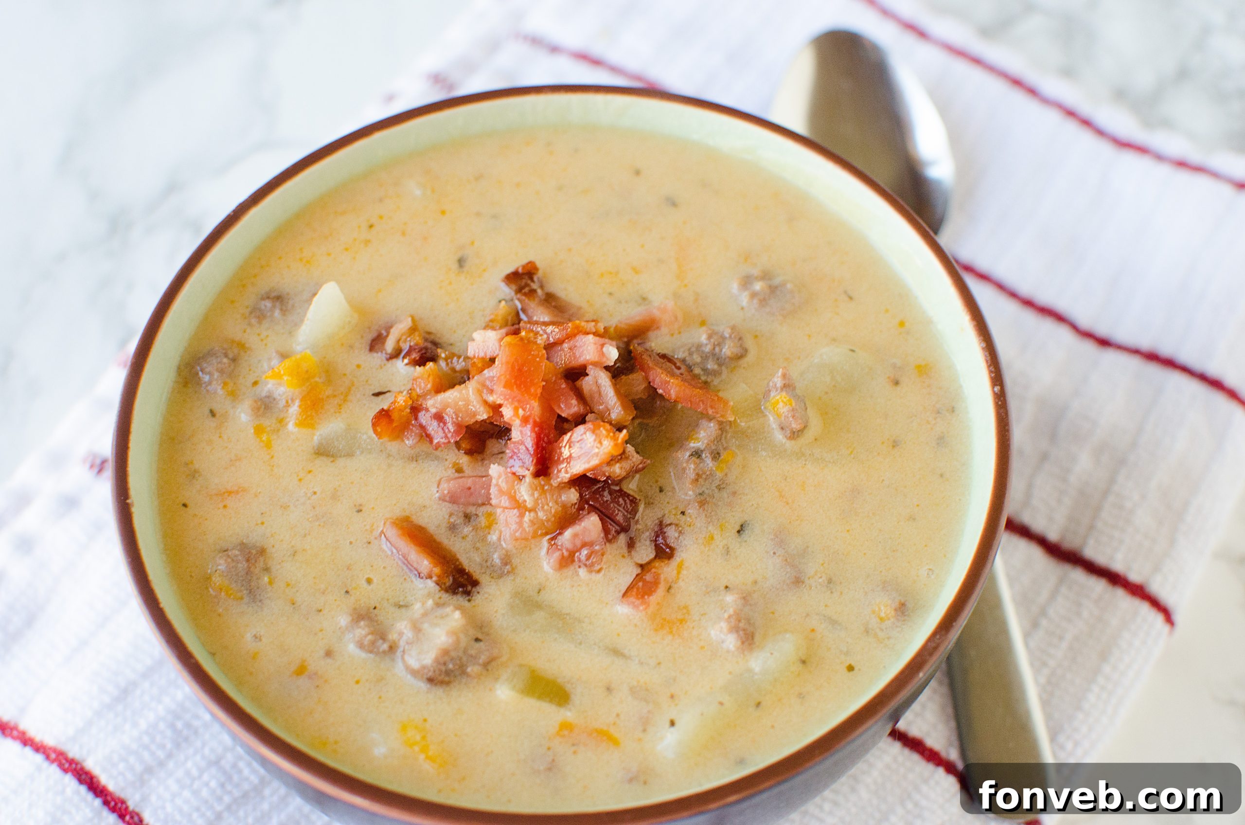 A full bowl of Slow Cooker Cheeseburger Soup, garnished with fresh herbs and a swirl of cream, ready to be enjoyed as a hearty meal. The backdrop suggests a cozy, home setting.