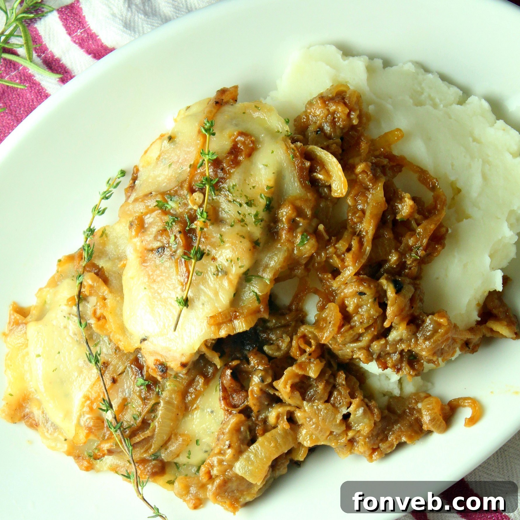 Close-up of a single smothered French onion pork chop, showcasing the layers of cheese and golden caramelized onions