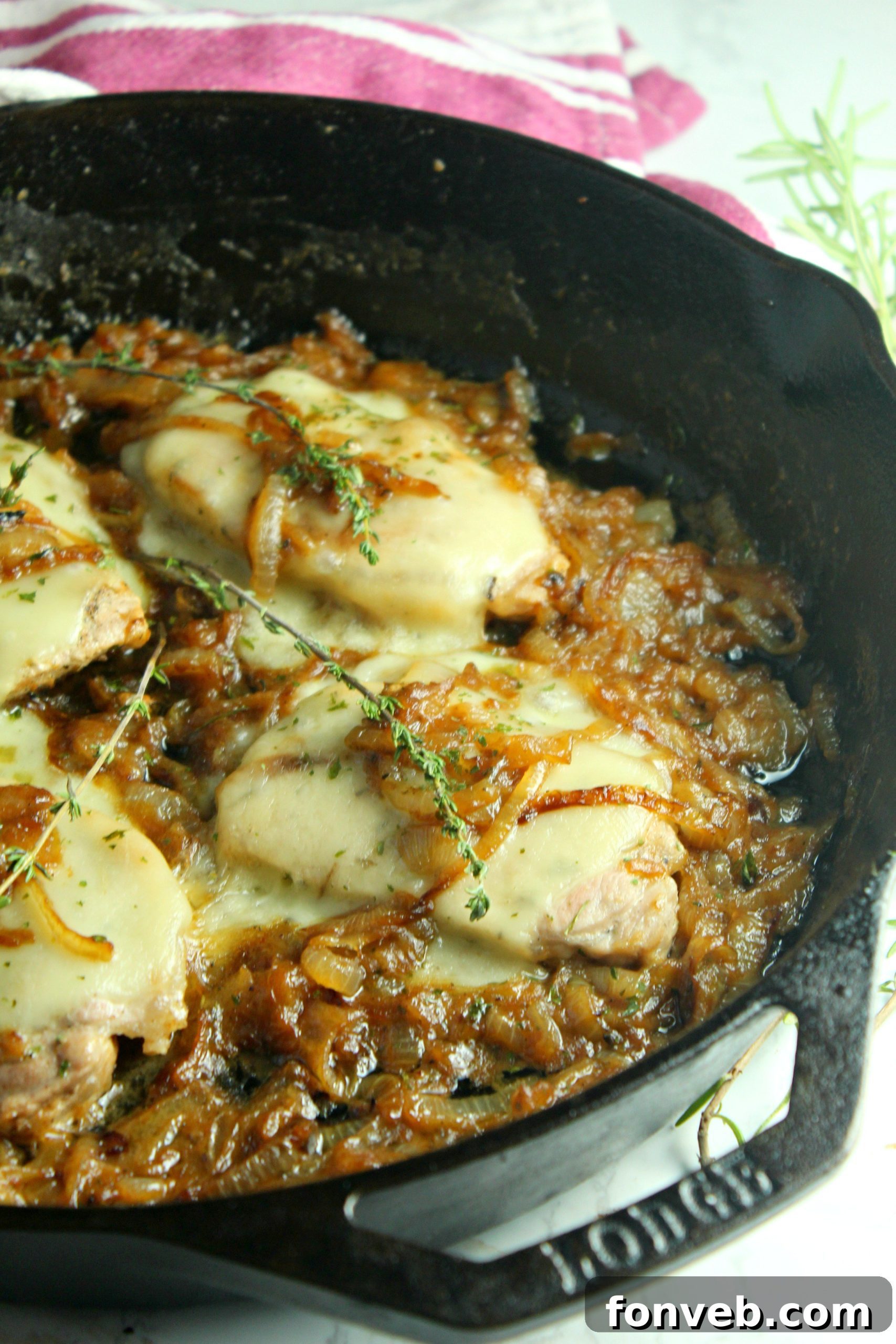 Ingredients for smothered French onion pork chops laid out on a cutting board, including fresh onions, pork chops, and cheeses