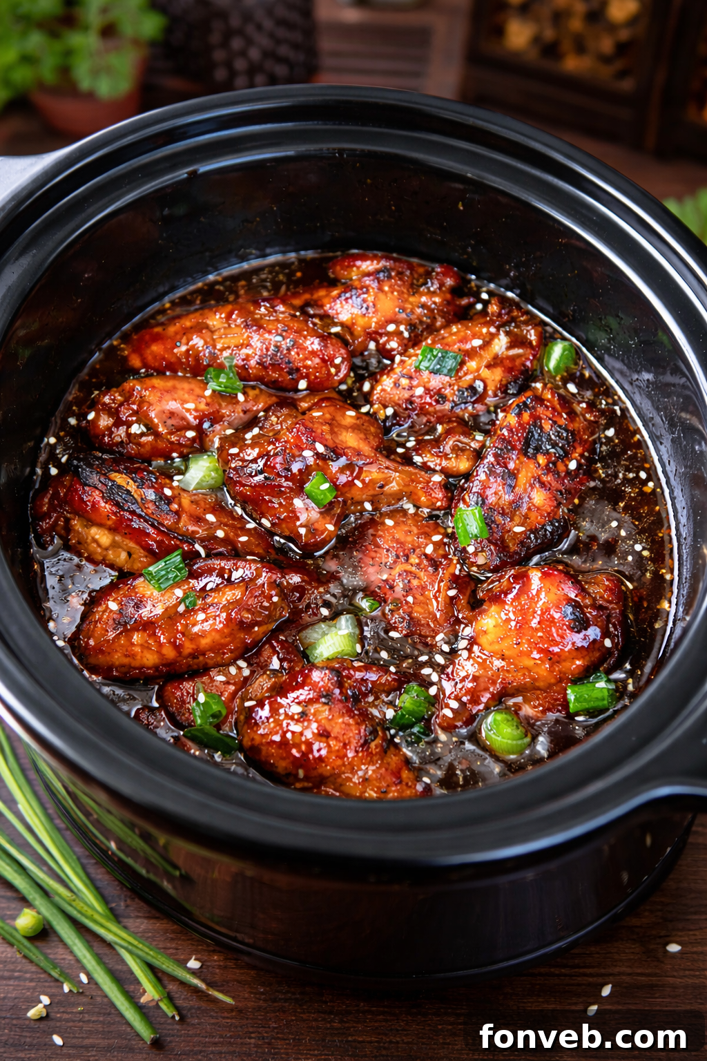 Slow Cooker Chicken Teriyaki Wings in a black slow cooker, glistening with sauce