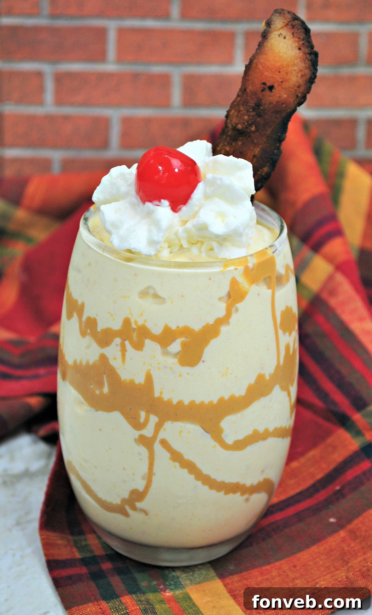A delicious Dirty Elvis Cocktail, garnished with whipped cream, a cherry, and a crispy bacon strip.