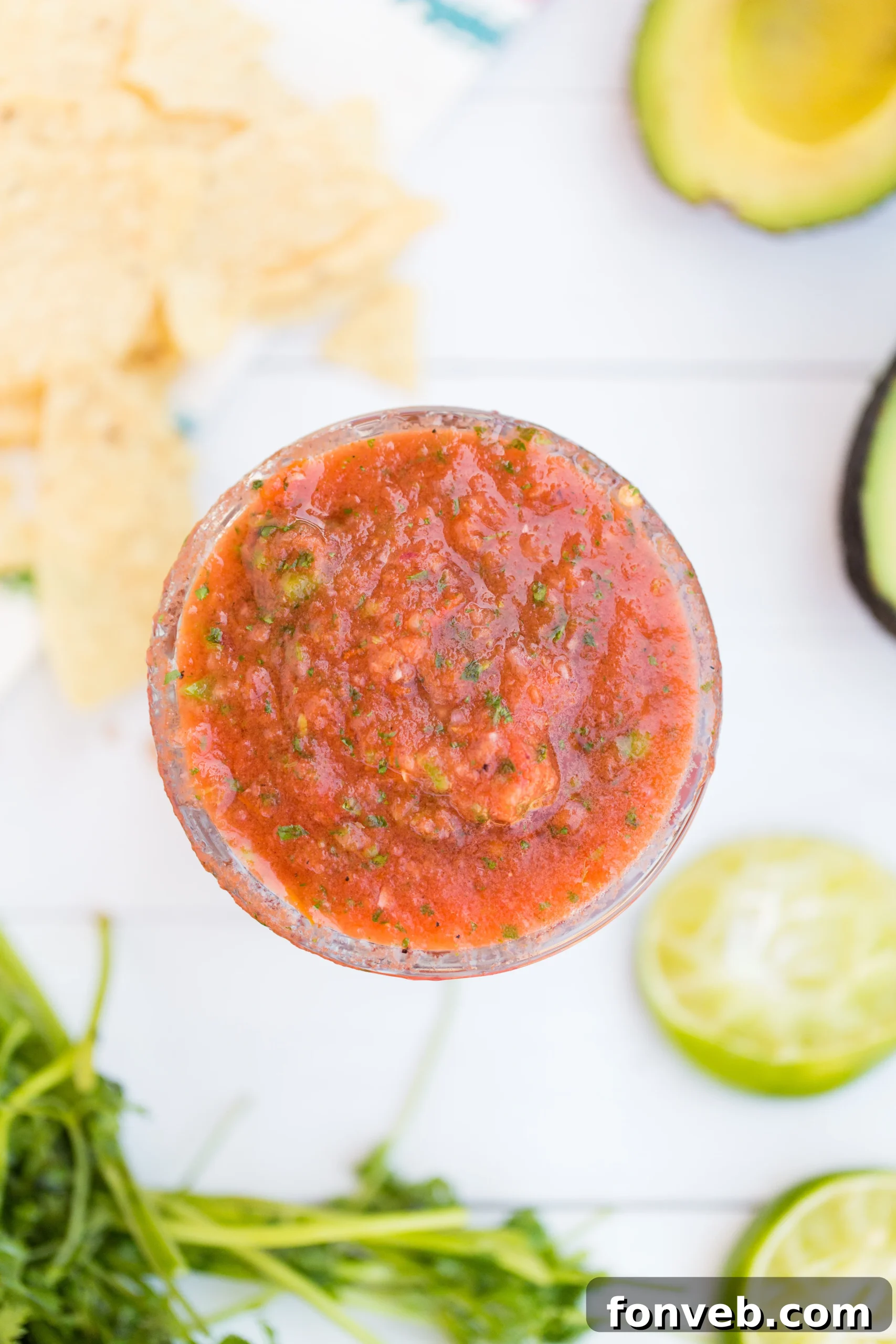 Signature Restaurant Salsa at Home 5 A person's hand holding a spoon, tasting a small portion of the freshly blended restaurant-style salsa for seasoning adjustments, emphasizing the customization aspect.