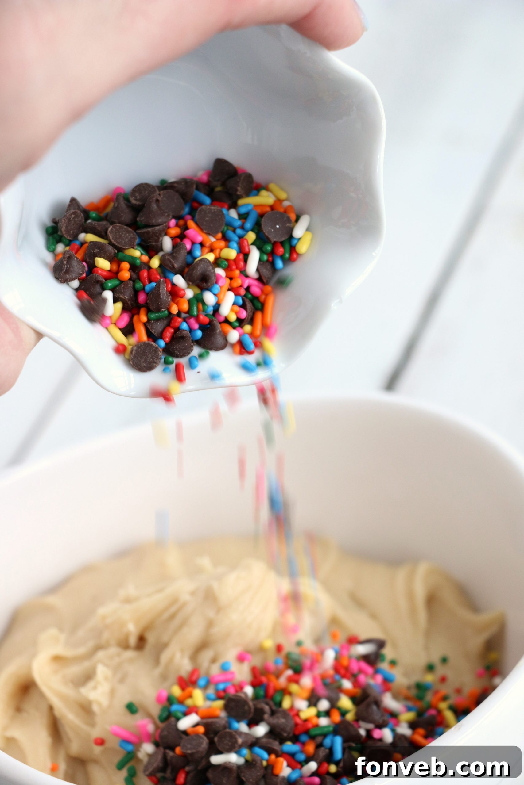 Overhead shot of a bowl of Funfetti Cookie Dough Dip with several cookies and a spoon, ready for dipping.