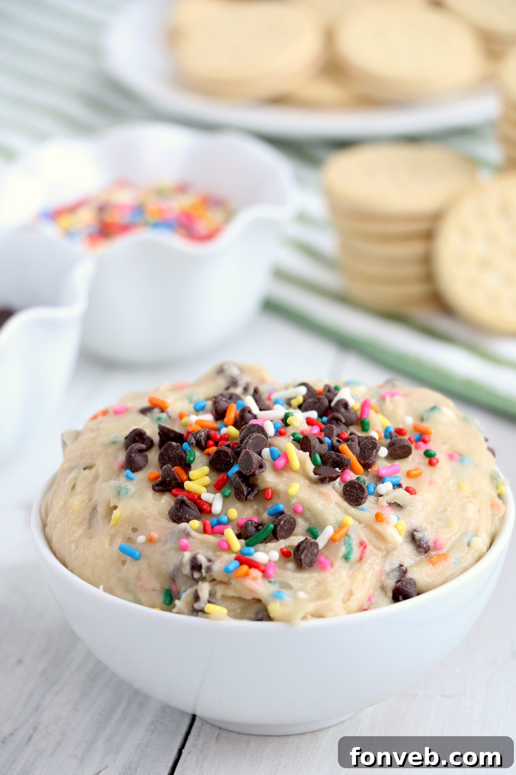 A bowl of Funfetti Cookie Dough Dip resting on a white table, ready to be enjoyed.