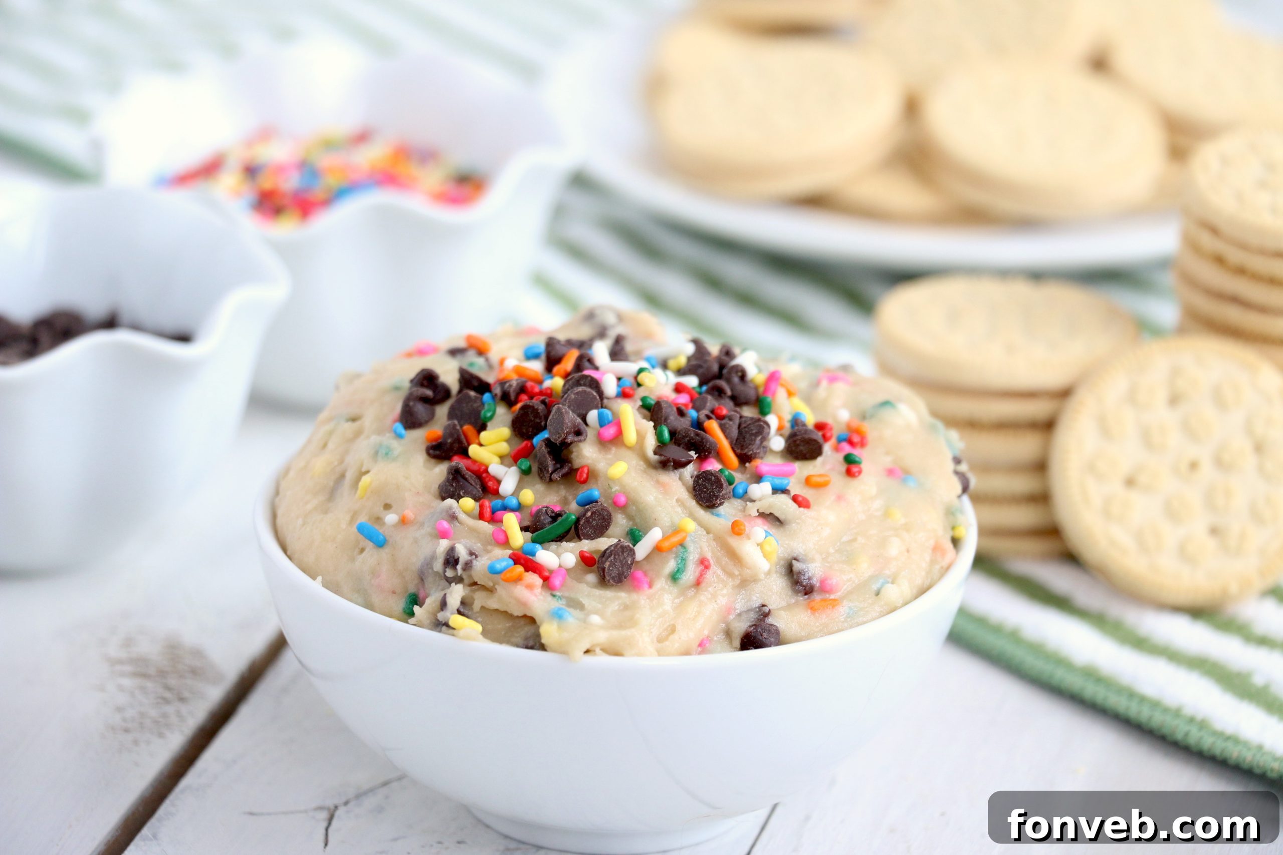 Overhead view of Funfetti Cookie Dough Dip in a white bowl, surrounded by various dippers like cookies and pretzels.