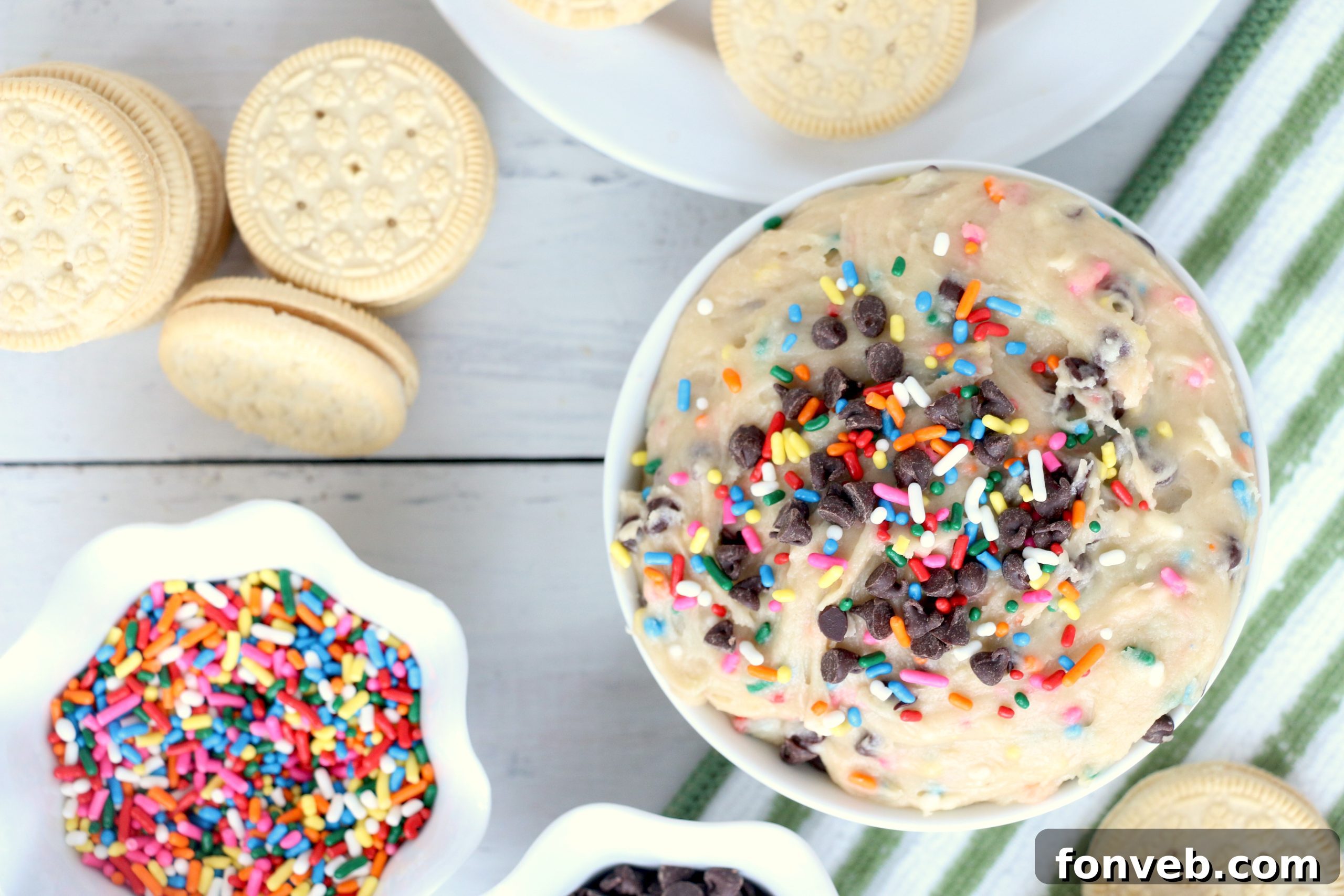 A person reaching for a spoonful of Funfetti Cookie Dough Dip, showcasing its creamy texture and sprinkles.