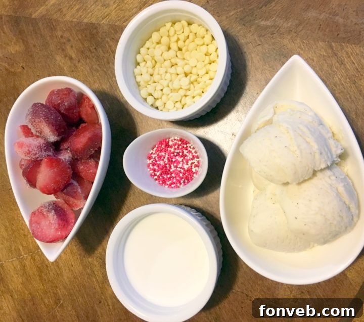 Fresh ingredients laid out for a strawberry white chocolate milkshake, including frozen strawberries, vanilla ice cream, half and half, and white chocolate chips.