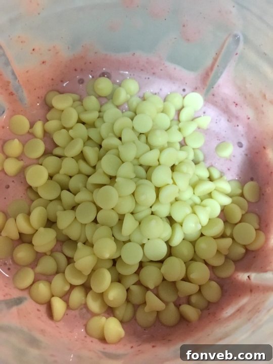 Pouring the blended Strawberry White Chocolate Milkshake into glasses.