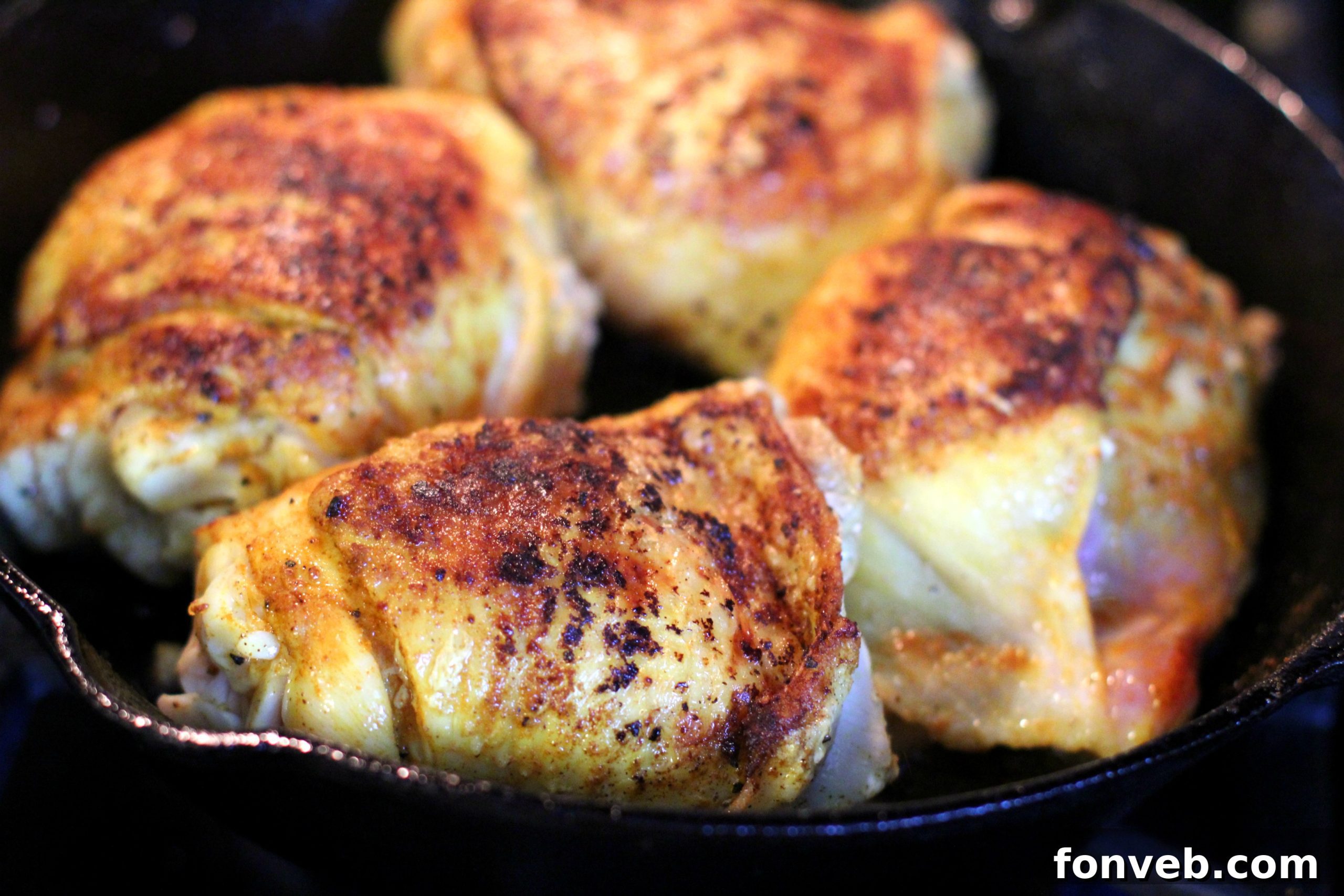Close-up of a skillet with cooked brown sugar lemon chicken, showcasing its crispy skin and glistening sauce.