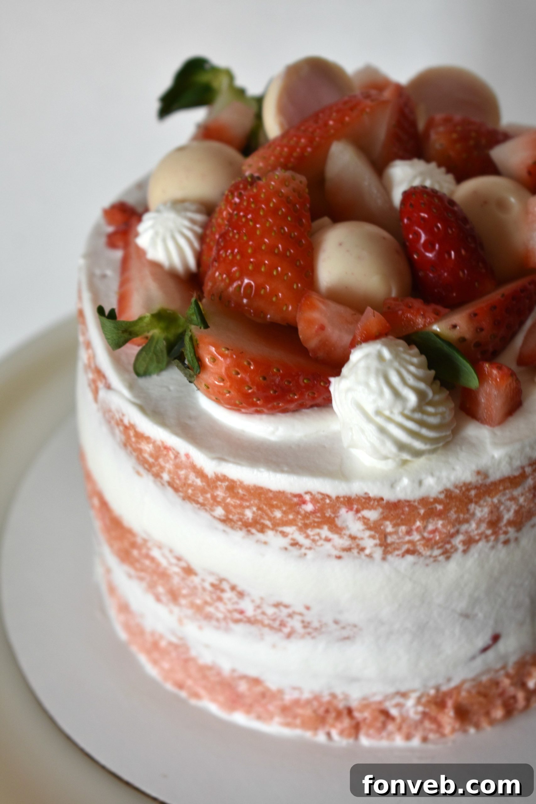 Strawberry Creamsicle Dream Cake 2 Close-up of a slice of Strawberry Creamsicle Layered Cake showing pink cake layers and white whipped frosting with fresh strawberry pieces
