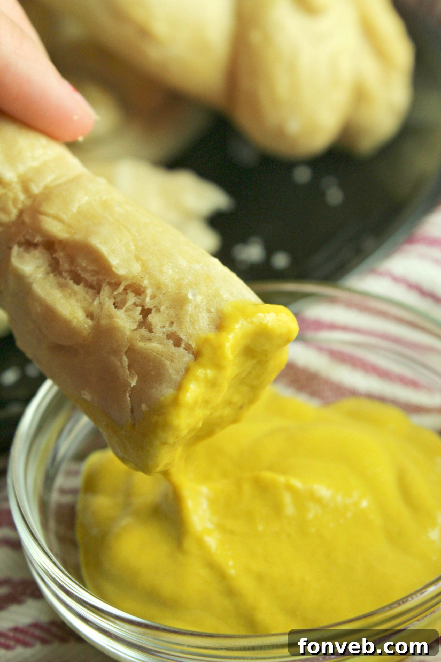 Warm Buttery Homemade Soft Pretzels 10 Hand holding a soft pretzel dipped in a bowl of mustard