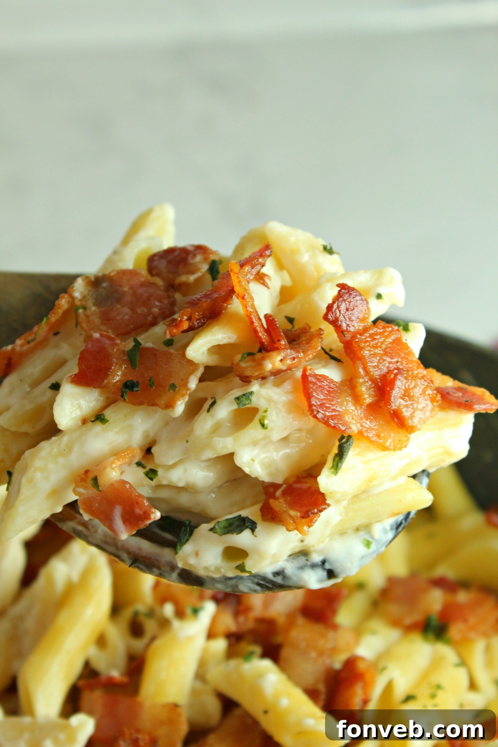 A large skillet containing the finished creamy bacon alfredo pasta, ready to be served.